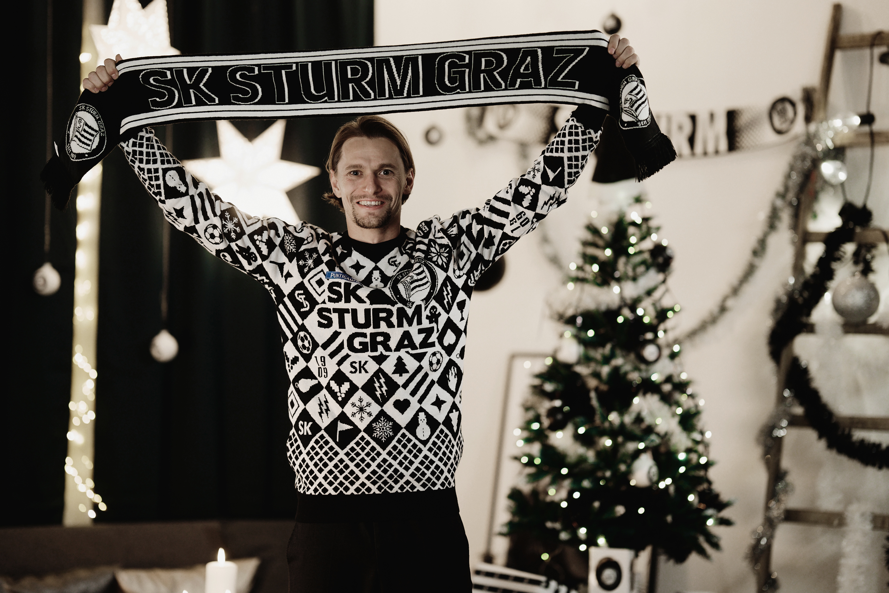 Die Person hält einen SK Sturm Fanschal in der Hand