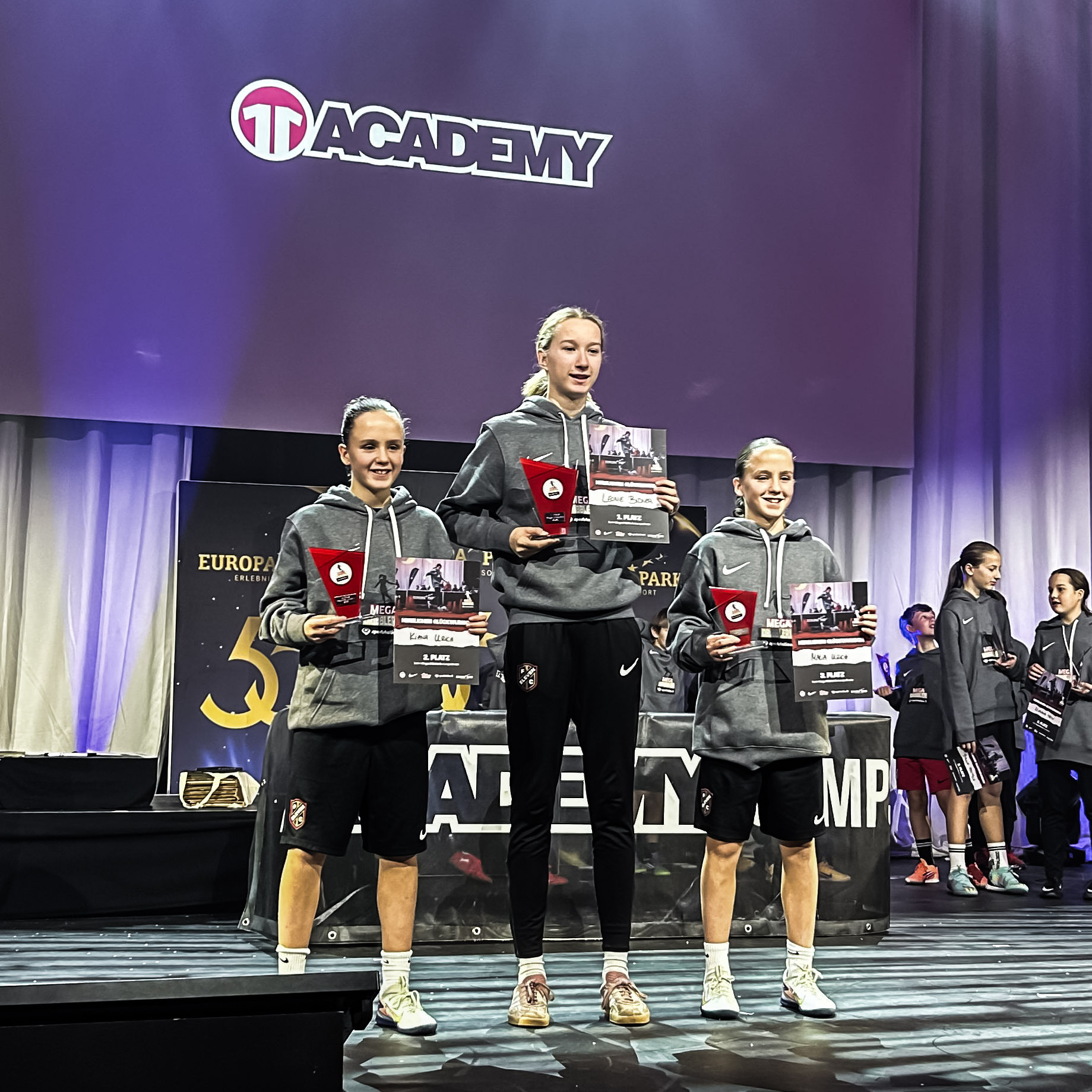 drei junge Mädchen halten Urkunden hoch