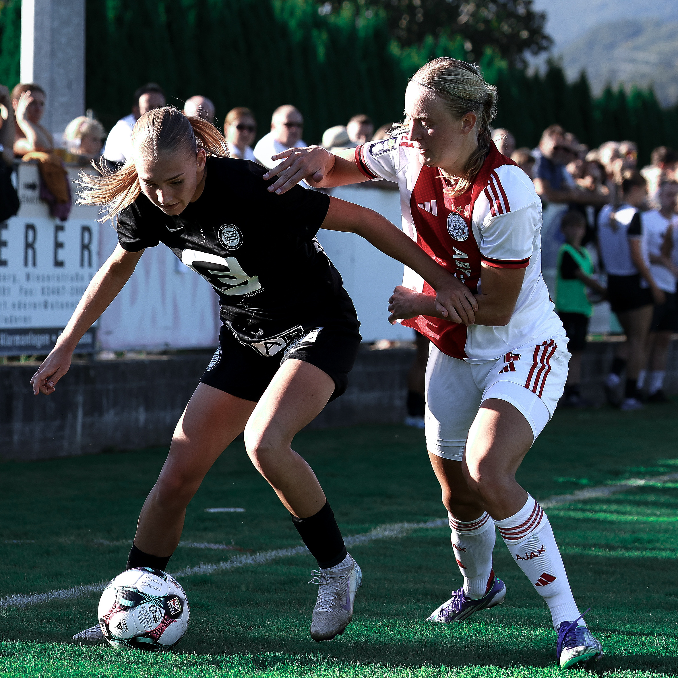 Eine Frau in schwarzem Trikot verteidigt den Ball gegen eine Frau in weiß rotem Trikot.
