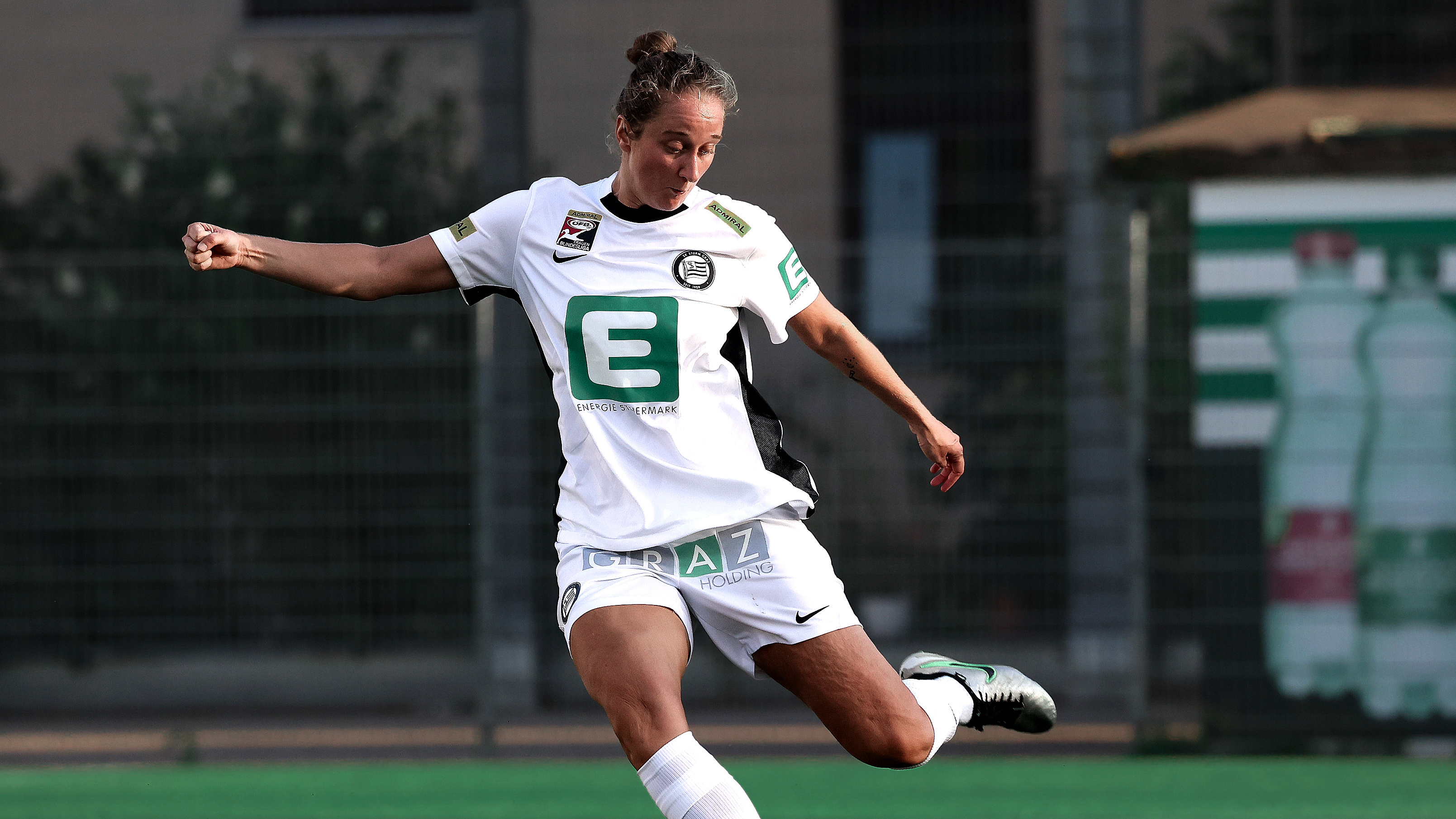 Eine frau in weißem Trikot holt zum Schuss aus.