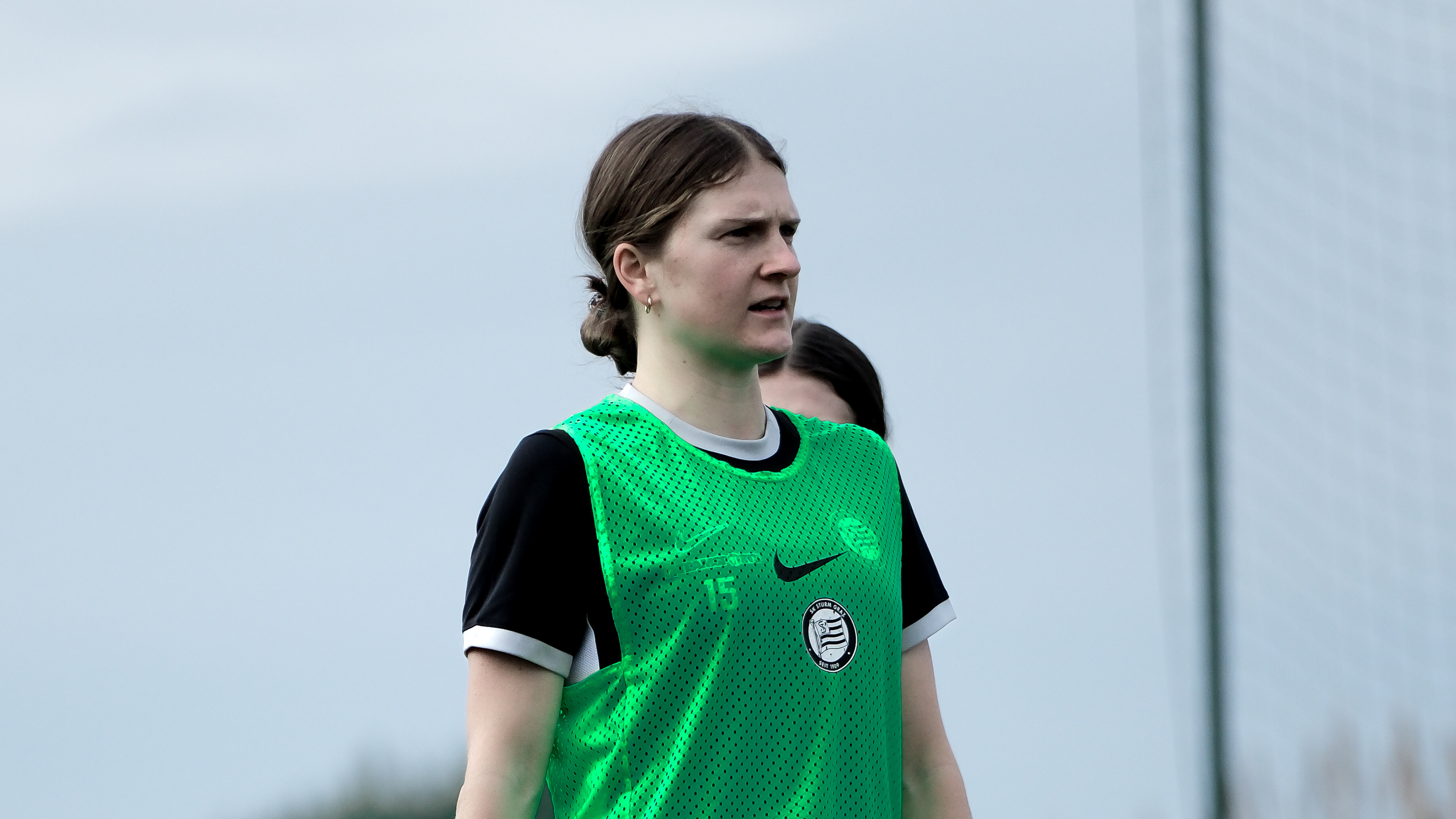 Eine Frau mit grünen Shirt sieht in die ferne.