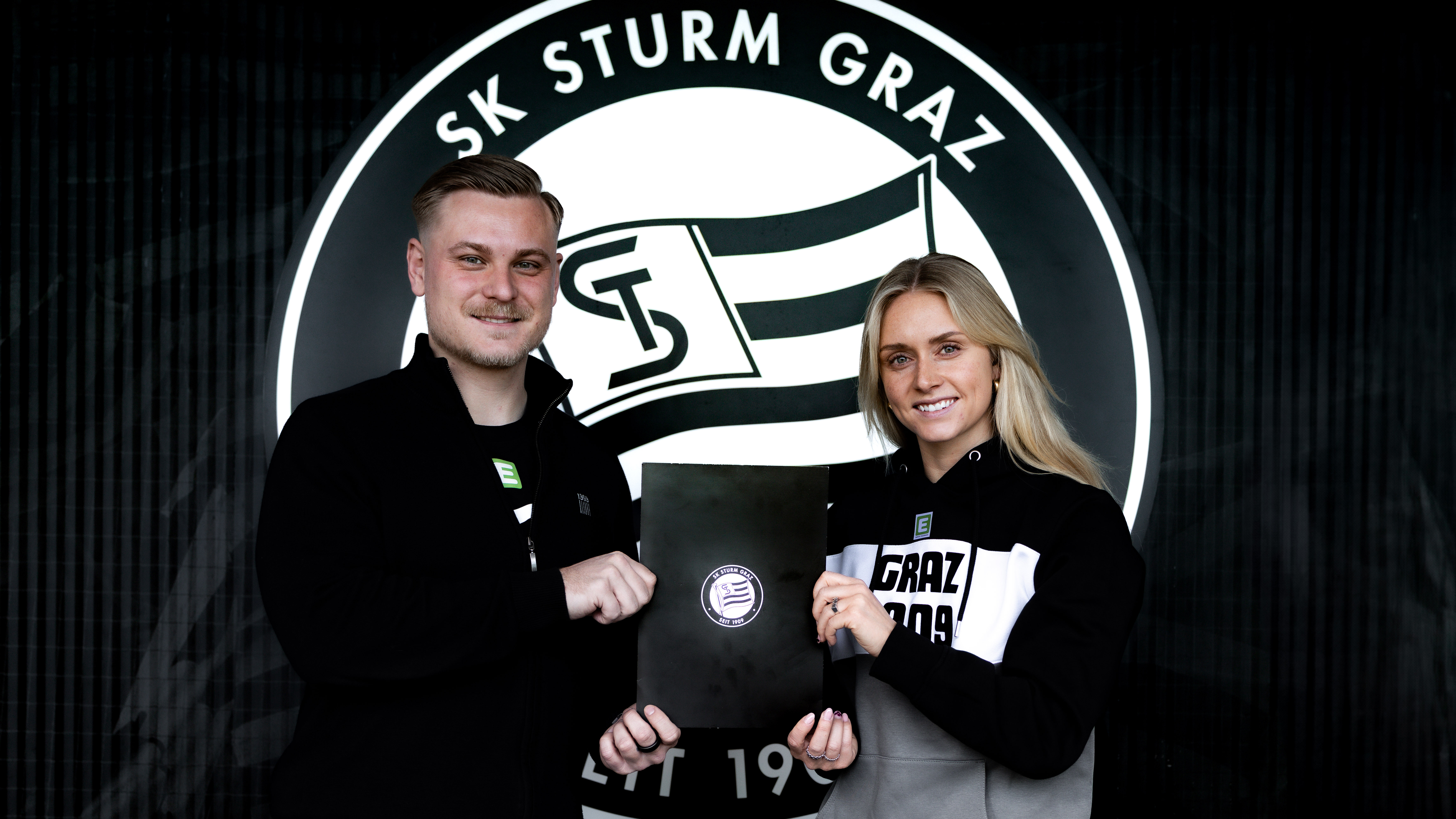 Ein Mann und eine Frau halten einen schwarzen Block hoch.