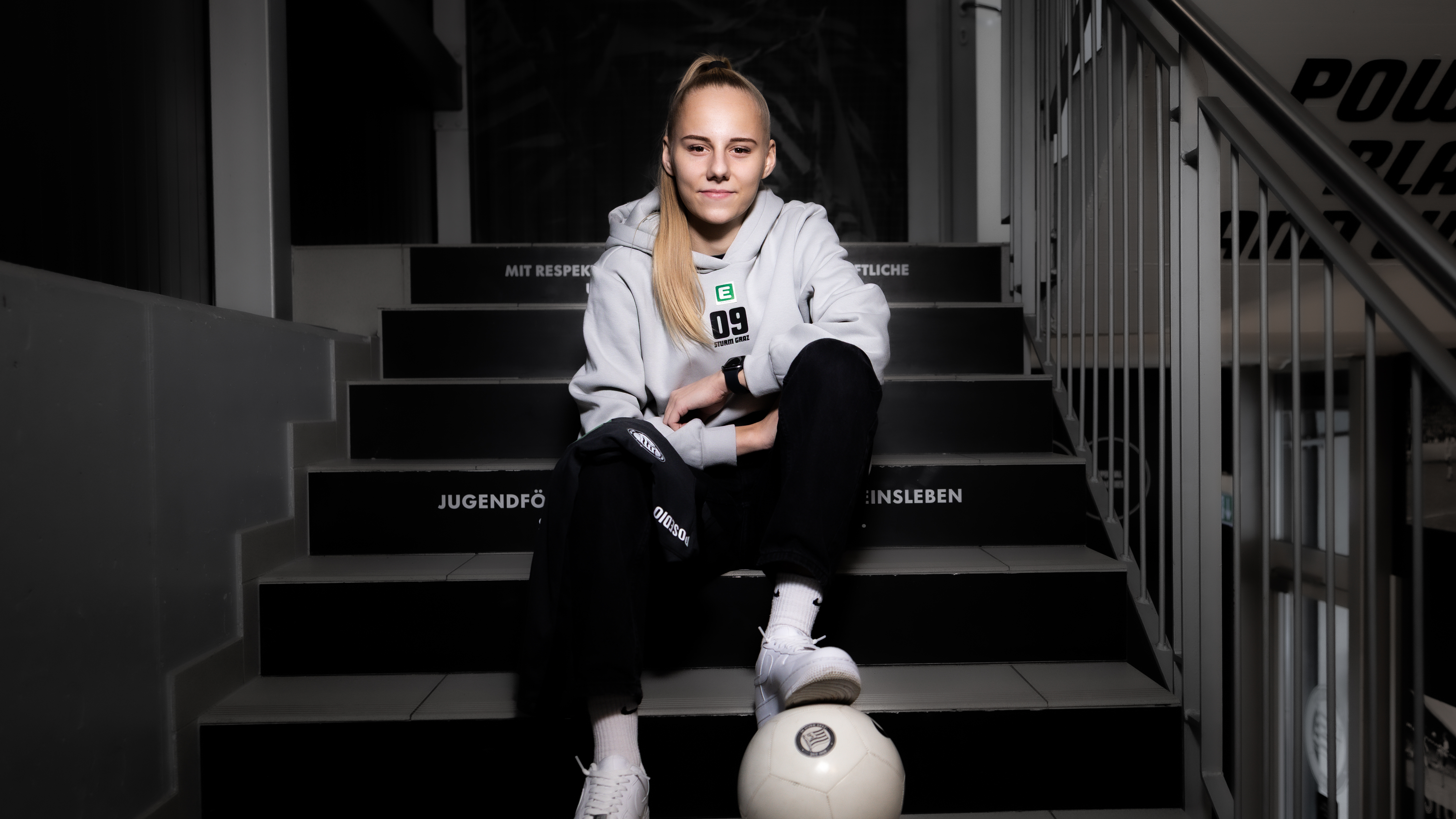 Eine Frau sitzt auf Stiegen und man sieht einen weißen Ball