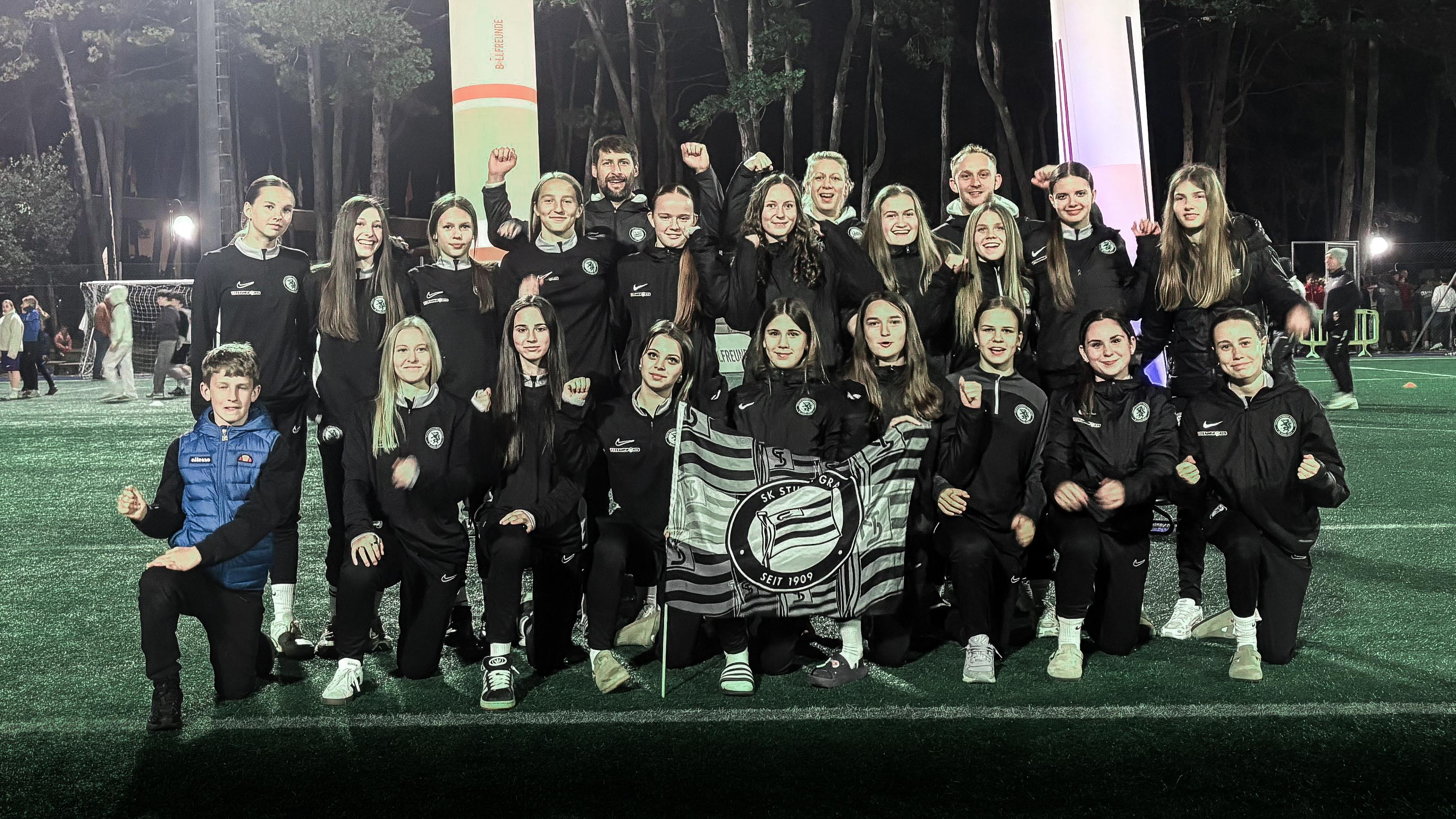 Viele junge Mädchen in schwarz halten eine Fahne hoch