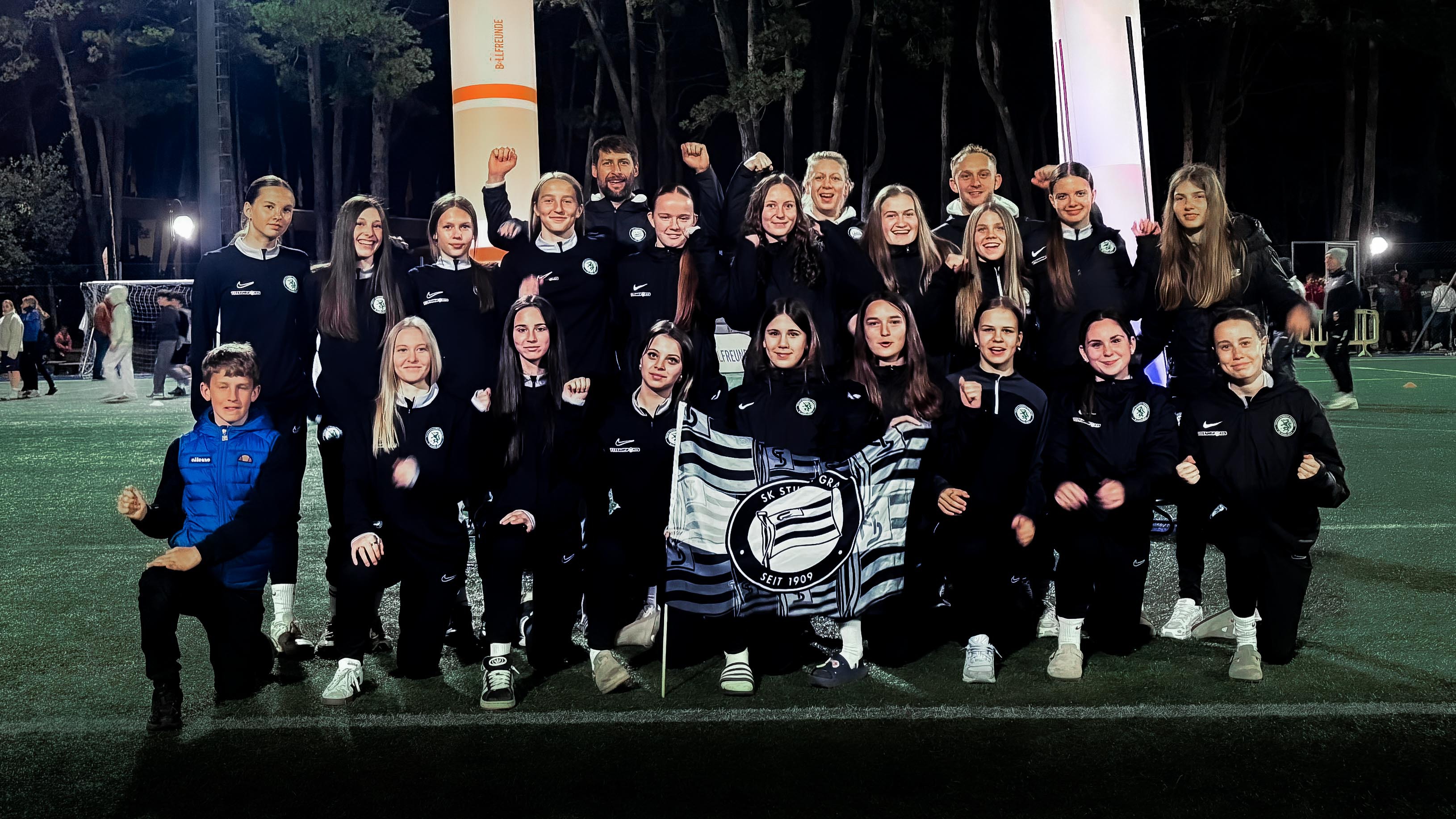 Viele junge Frauen in schwarz halten eine Fahne hoch