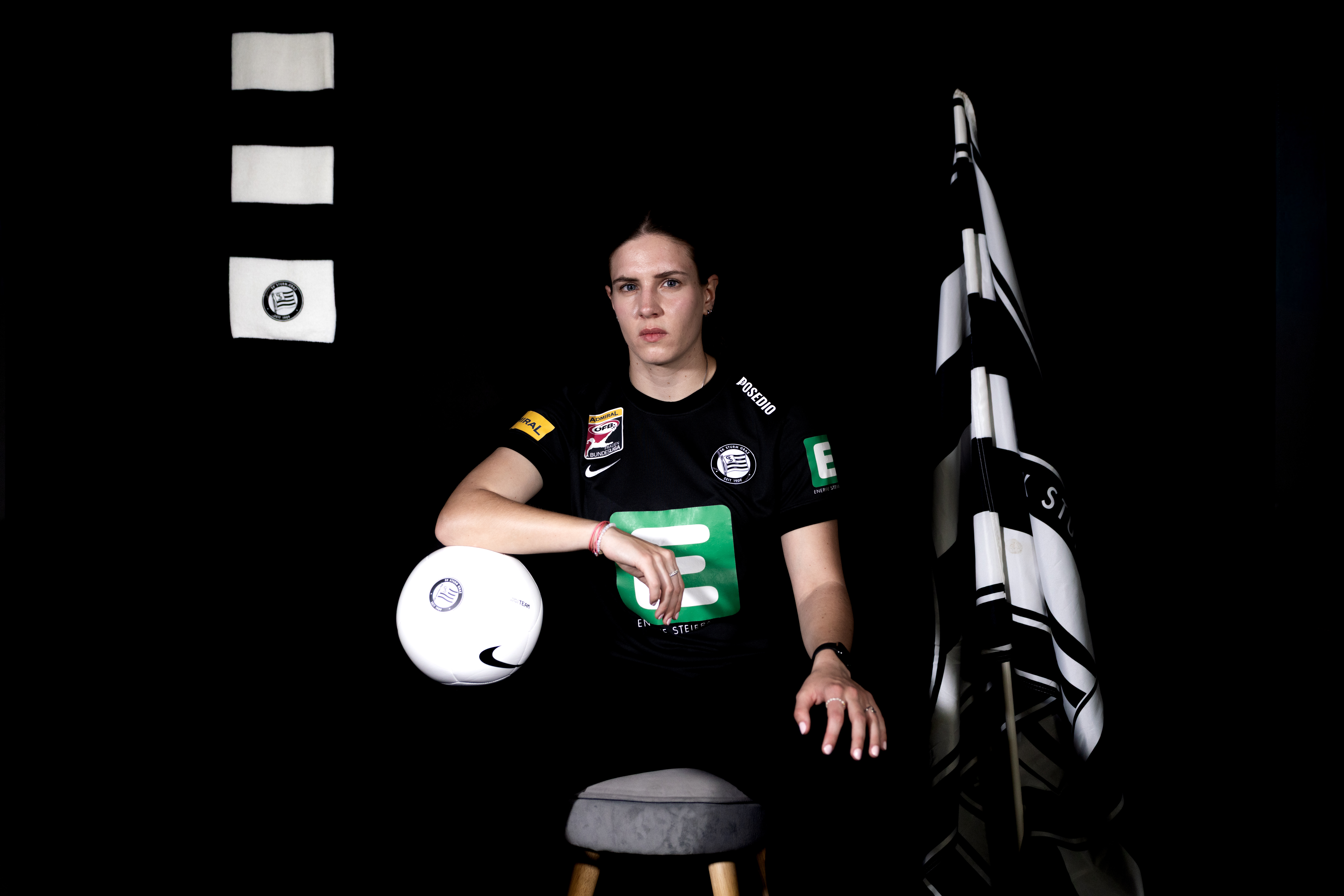 Eine Frau in schwarzem Trikot sitz auf einem Stuhl und lächelt.