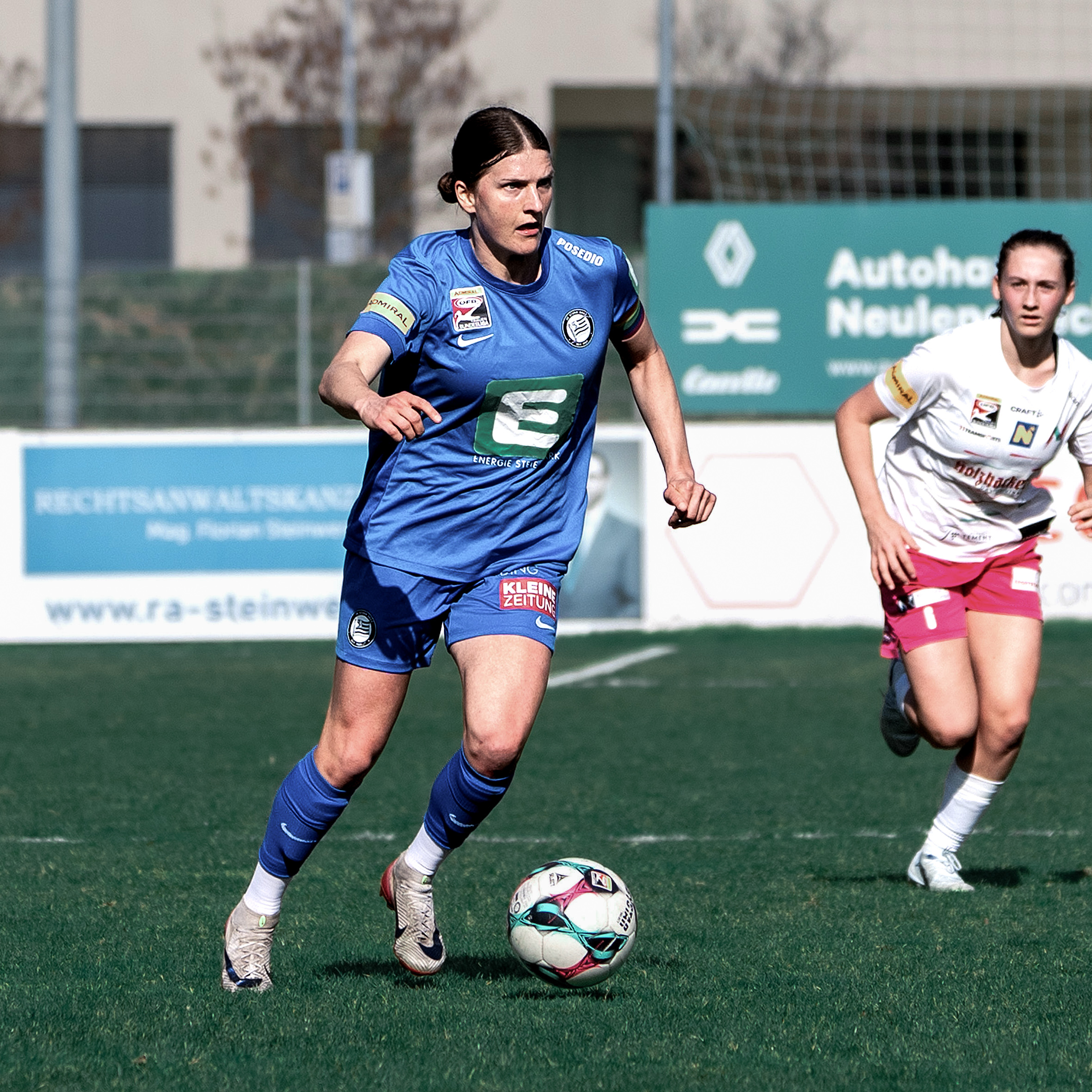 Eine Frau in blauem Trikot hat den Ball am Fuß.