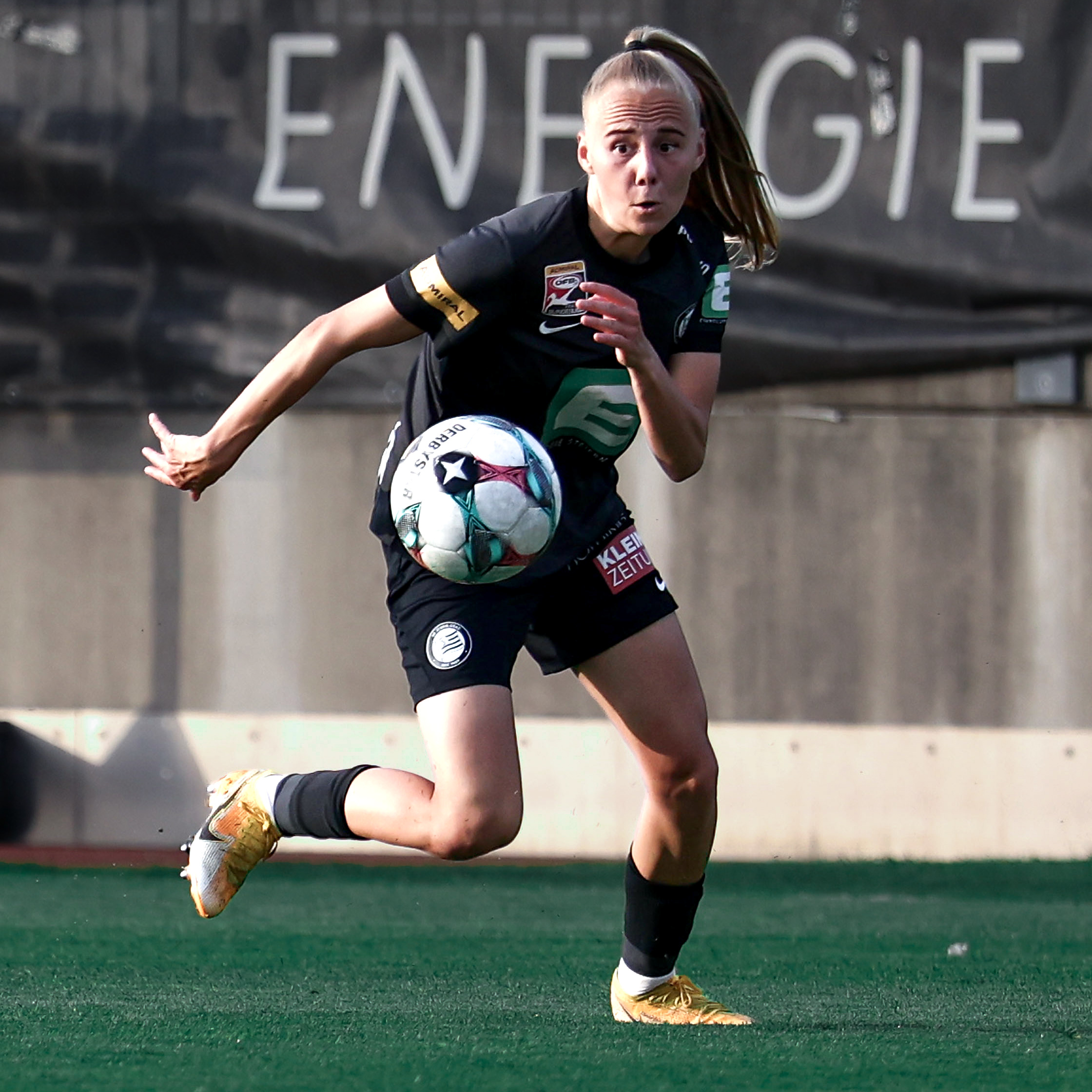 Eine Frau in schwarzem Trikot läuft dem Ball nach.