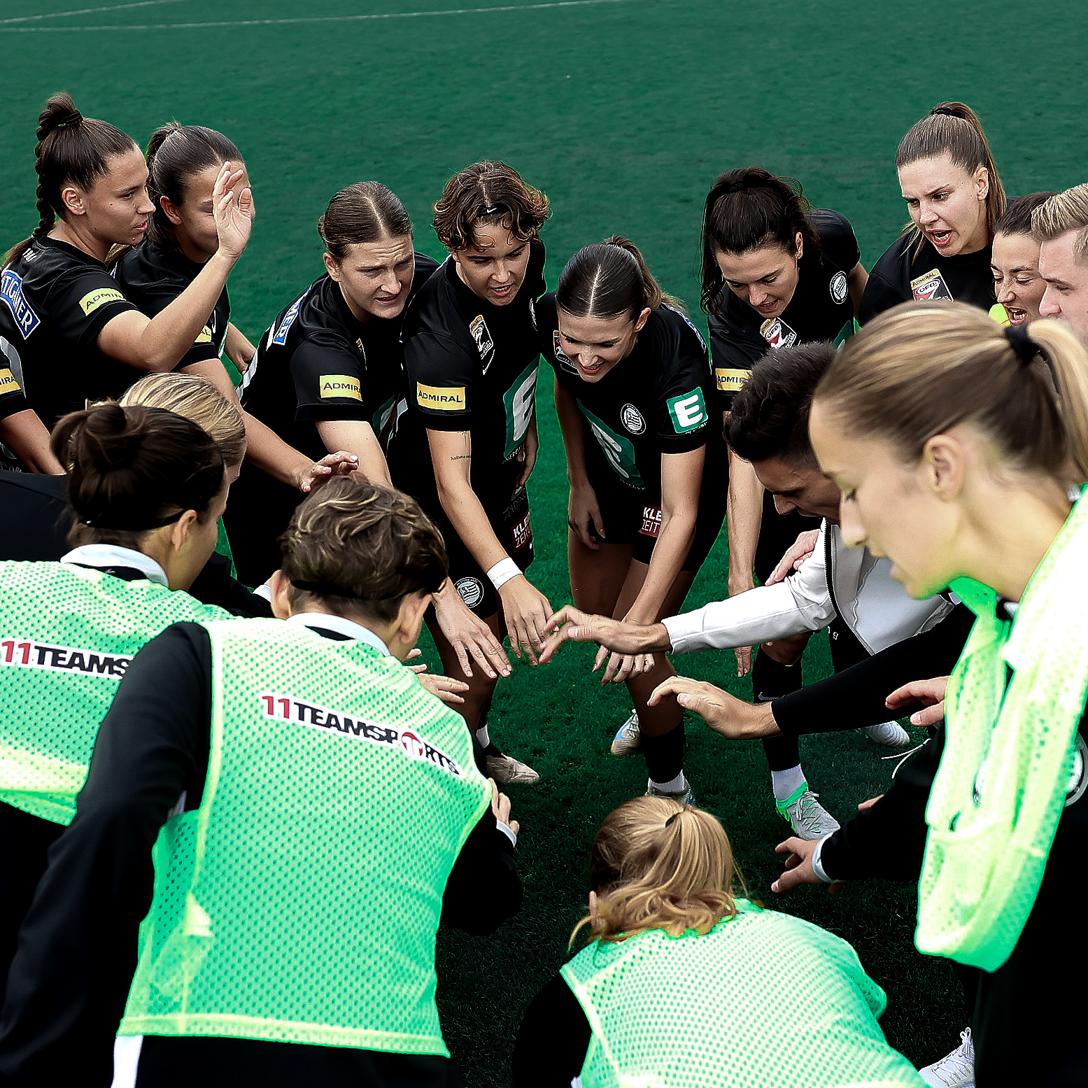 Eine Gruppe voller Frauen hält die Hände zusammen und schreit energisch.