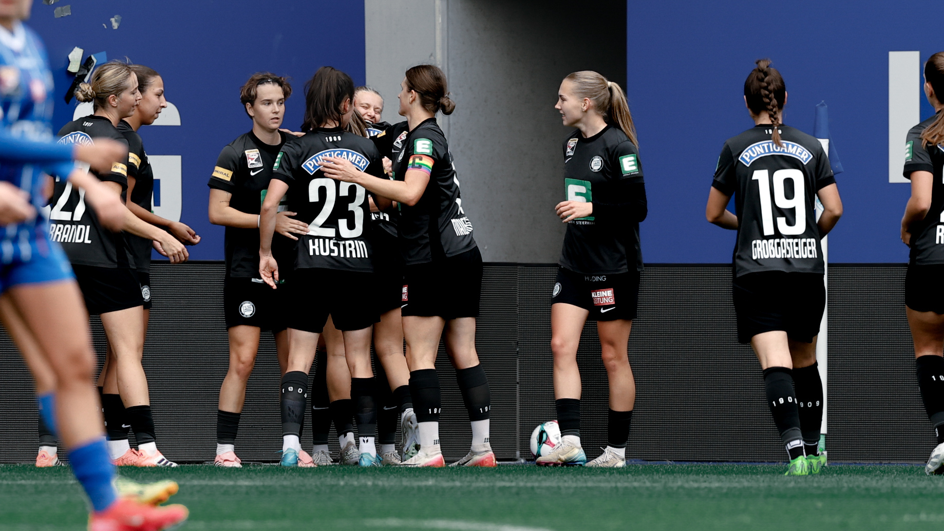 Eine Gruppe Frauen mit schwarzen Trikots freuen sich zusammen.