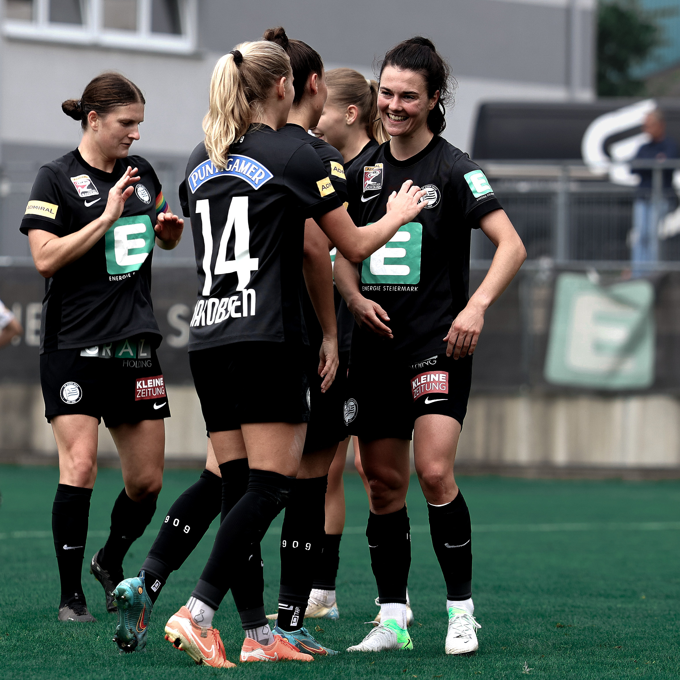 Zwei Frauen im schwarzem Trikot freuen sich miteinander.