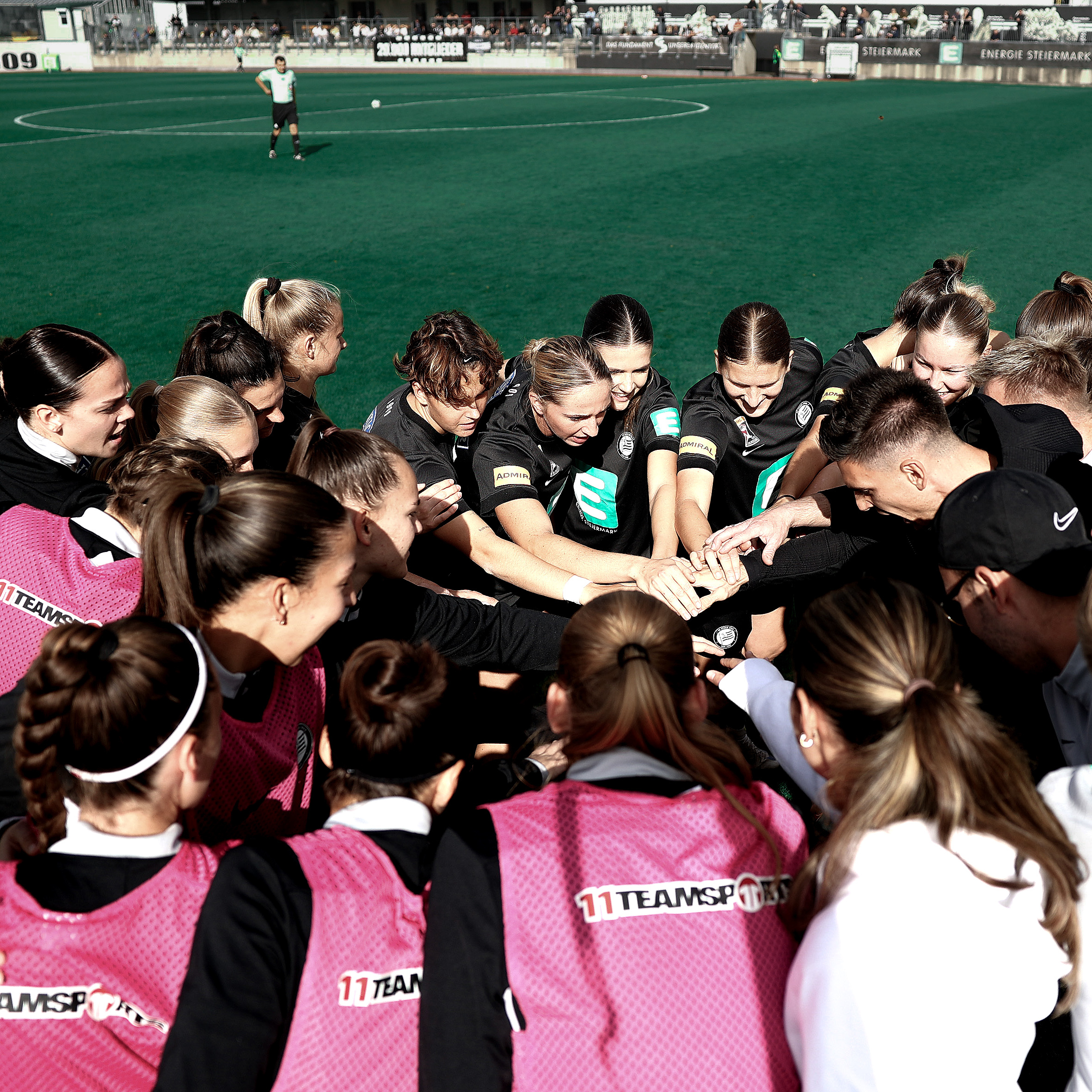 Ein Team steht in einem Kreis und halten die Hände zusammen.