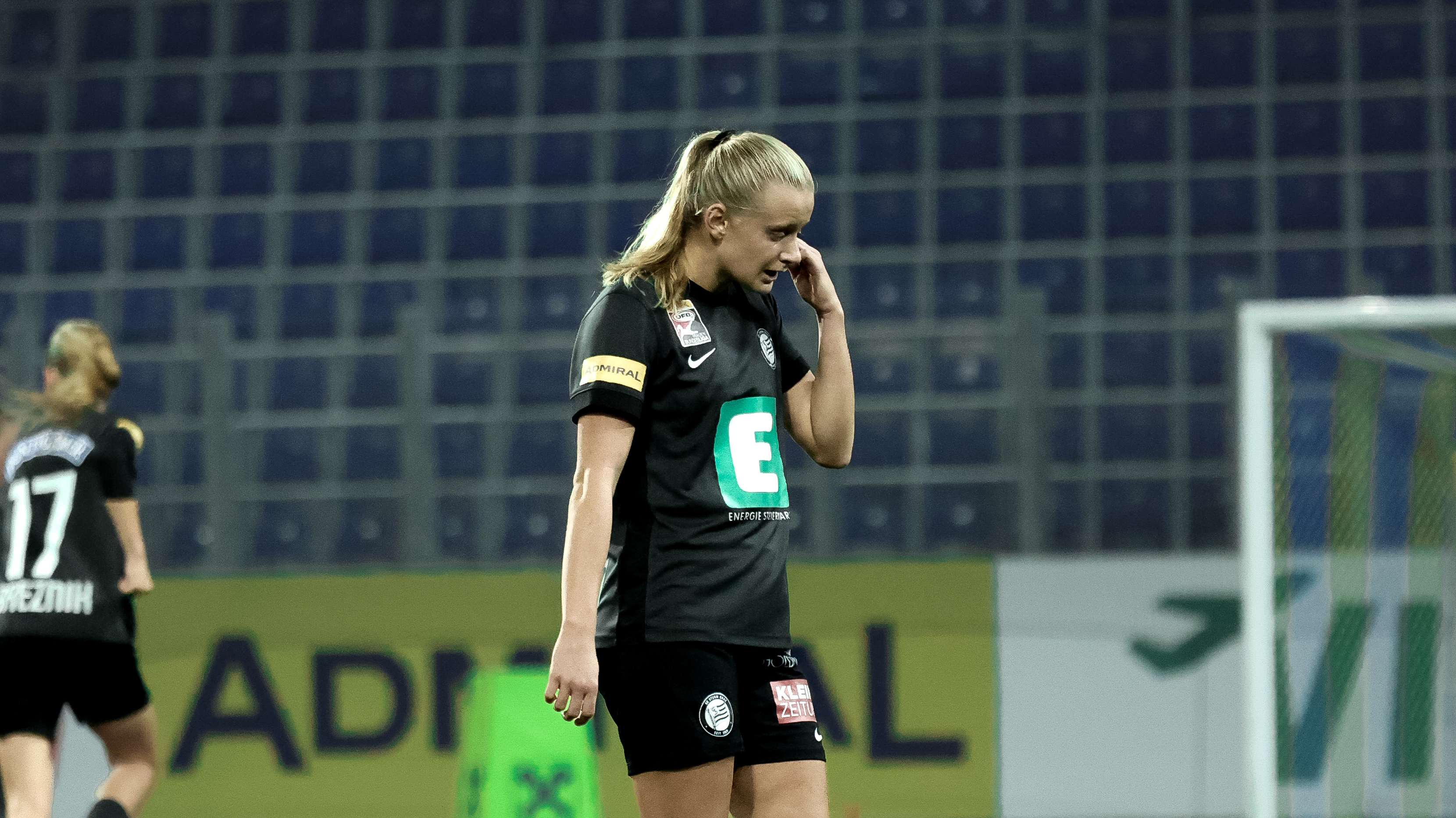 Eine Frau im schwarzem Trikot sieht traurig nach unten.