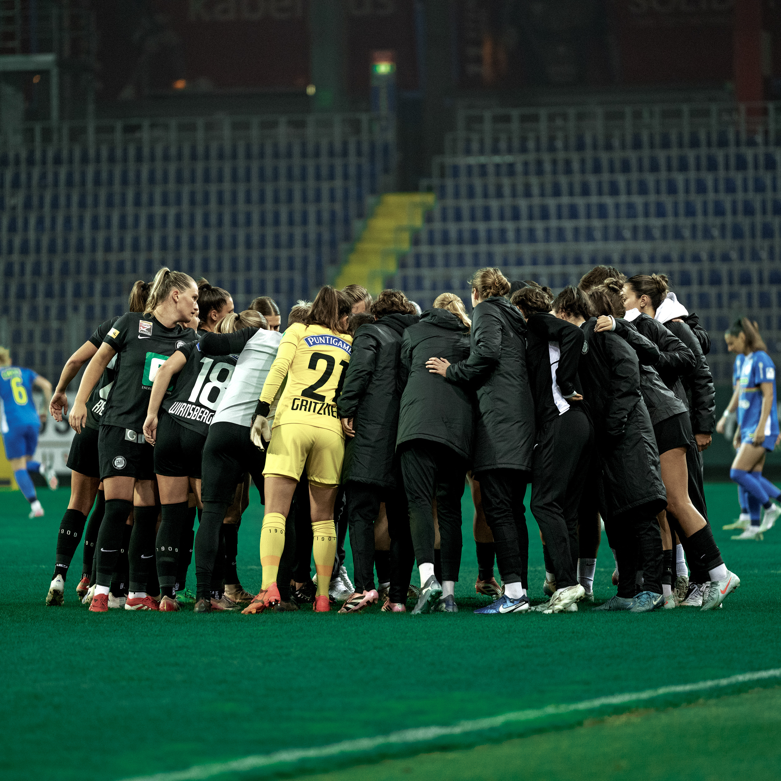 Eine Gruppe voller Menschen stehen im Kreis zusammen.