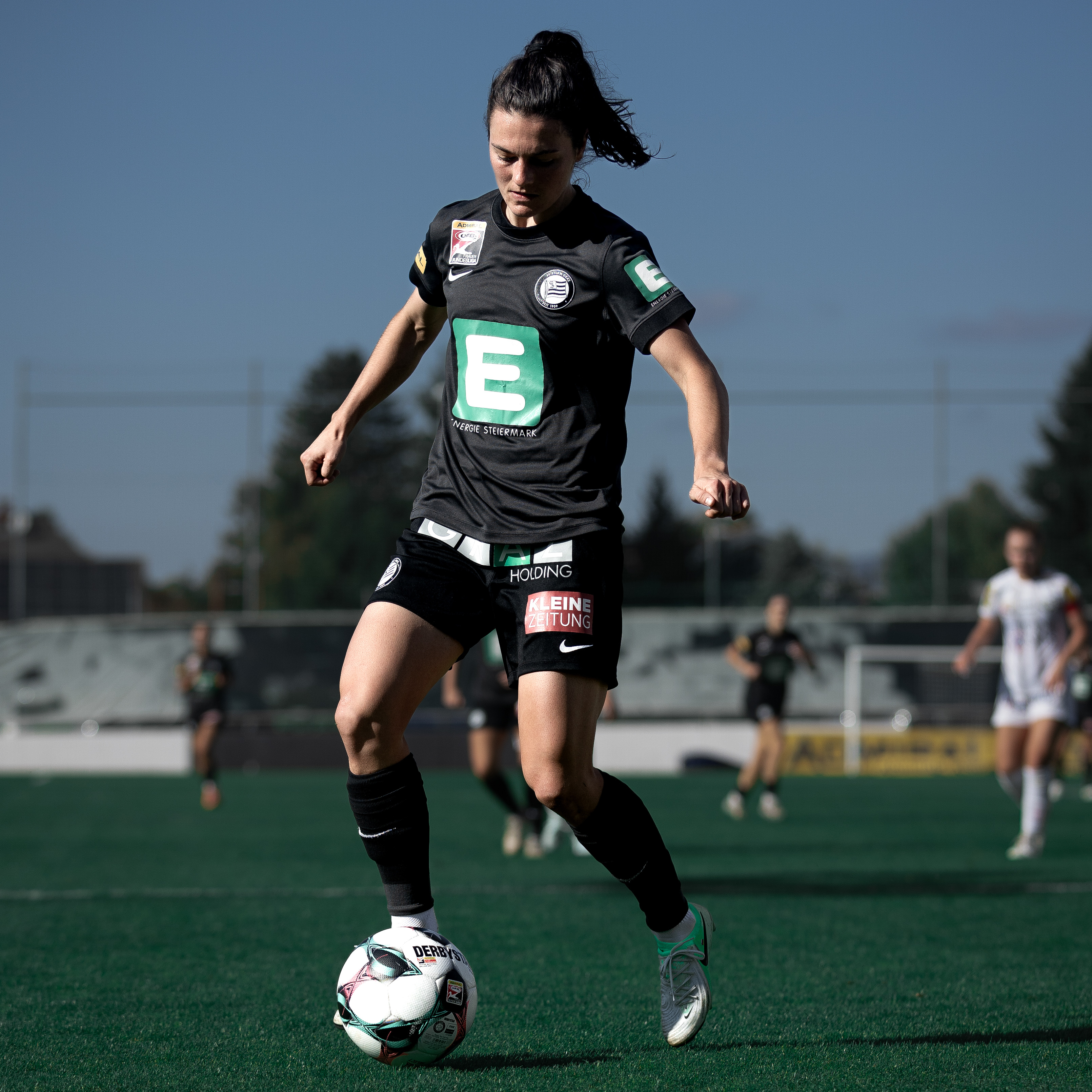 Eine Frau im schwarzen Trikot hat den Ball am Fuß.