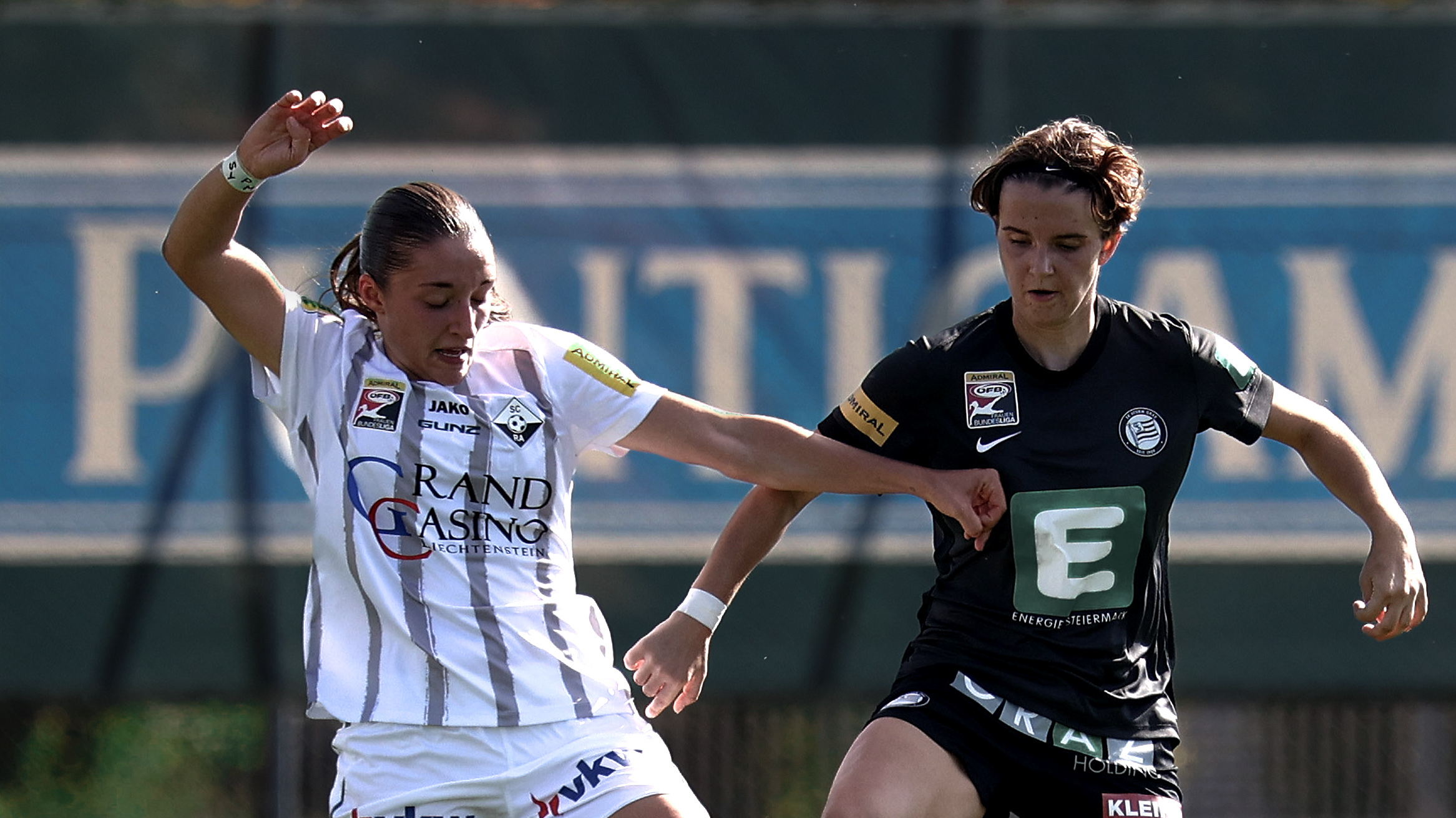 Eine Frau in schwarzem Trikot und eine Frau in weißem Trikot führen einen Zweikampf.