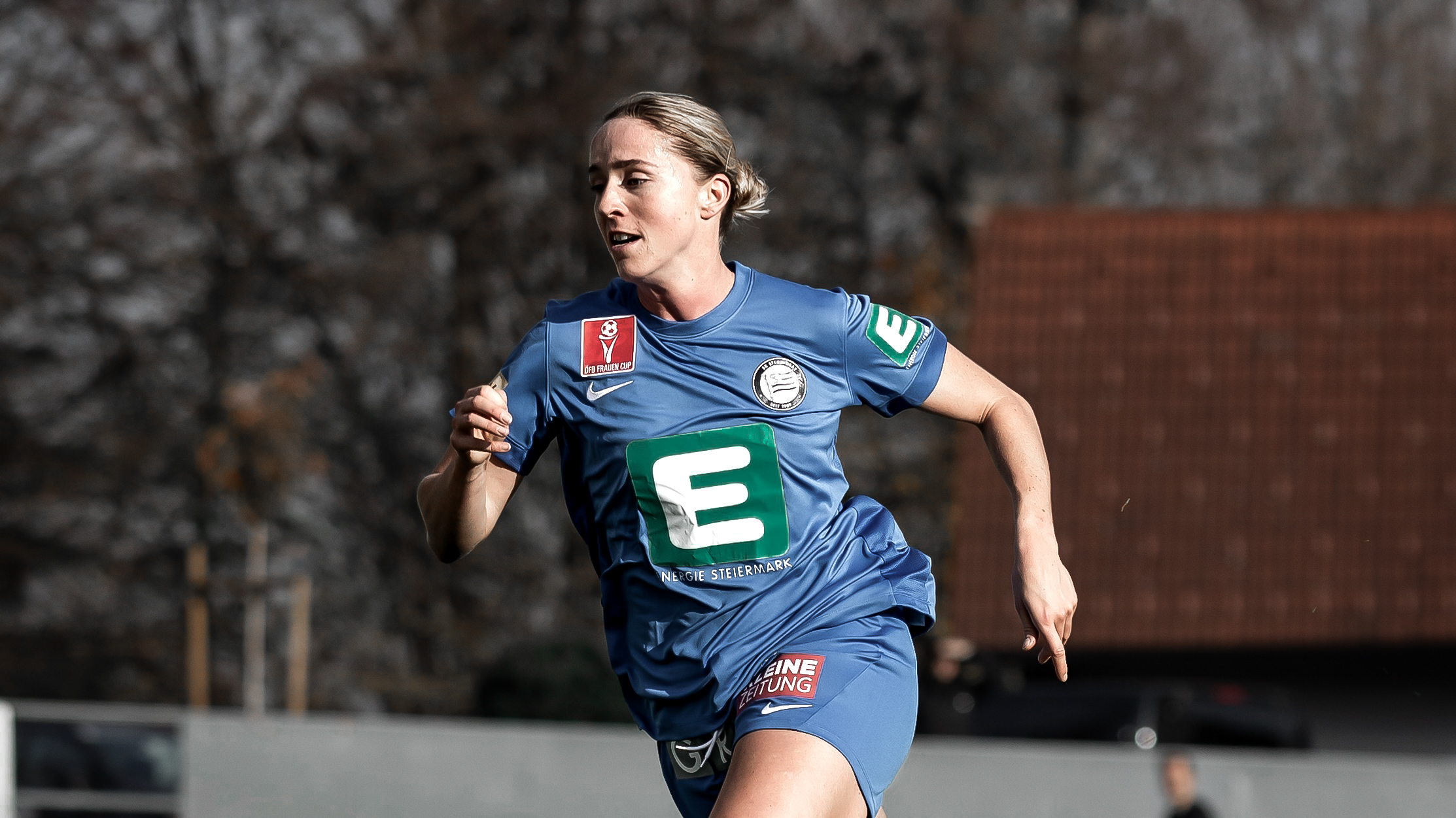 Eine Frau in blauen Trikot läuft nach links.