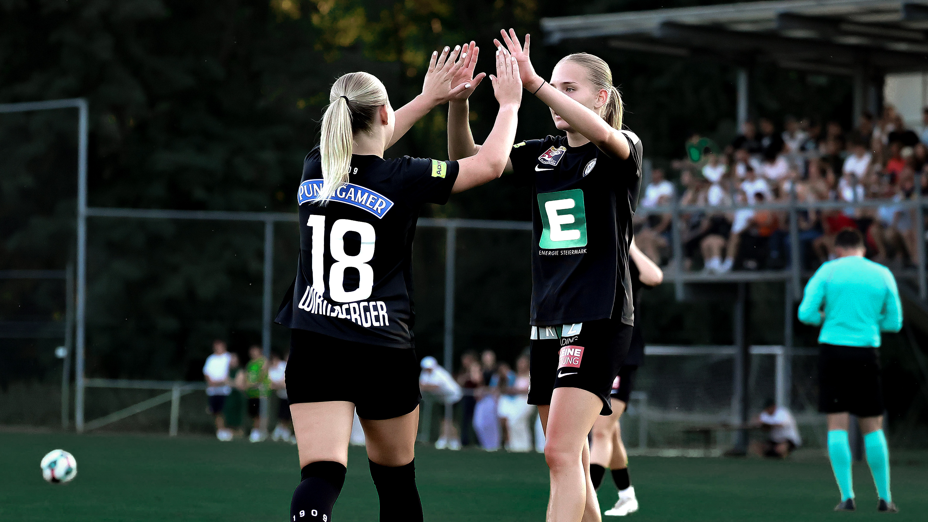 Zwei Frauen in schwarzem Trikot heben die Hände und klatschen gegenseitig ein.