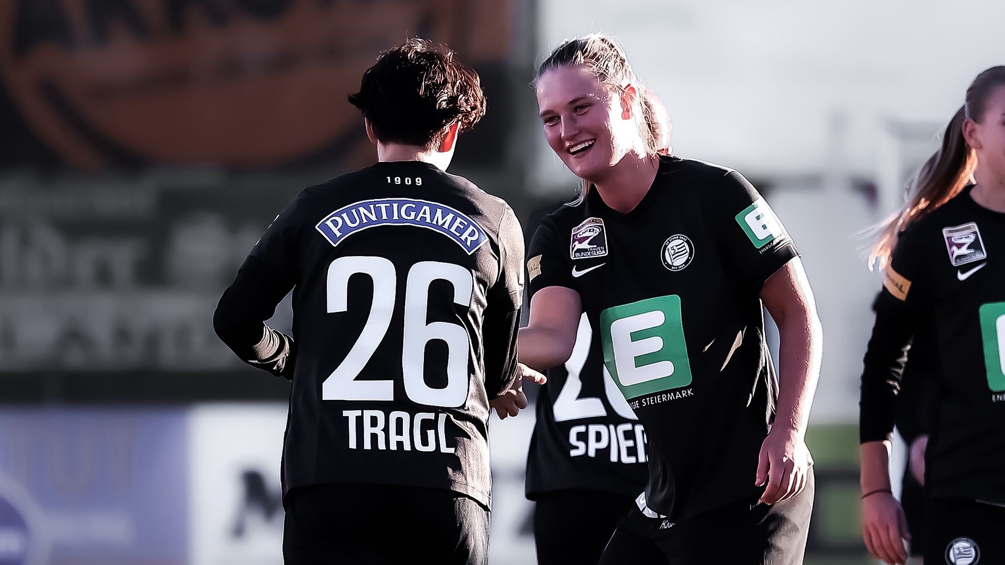 Zwei Frauen in schwarzen Trikots freuen sich gemeinsam.