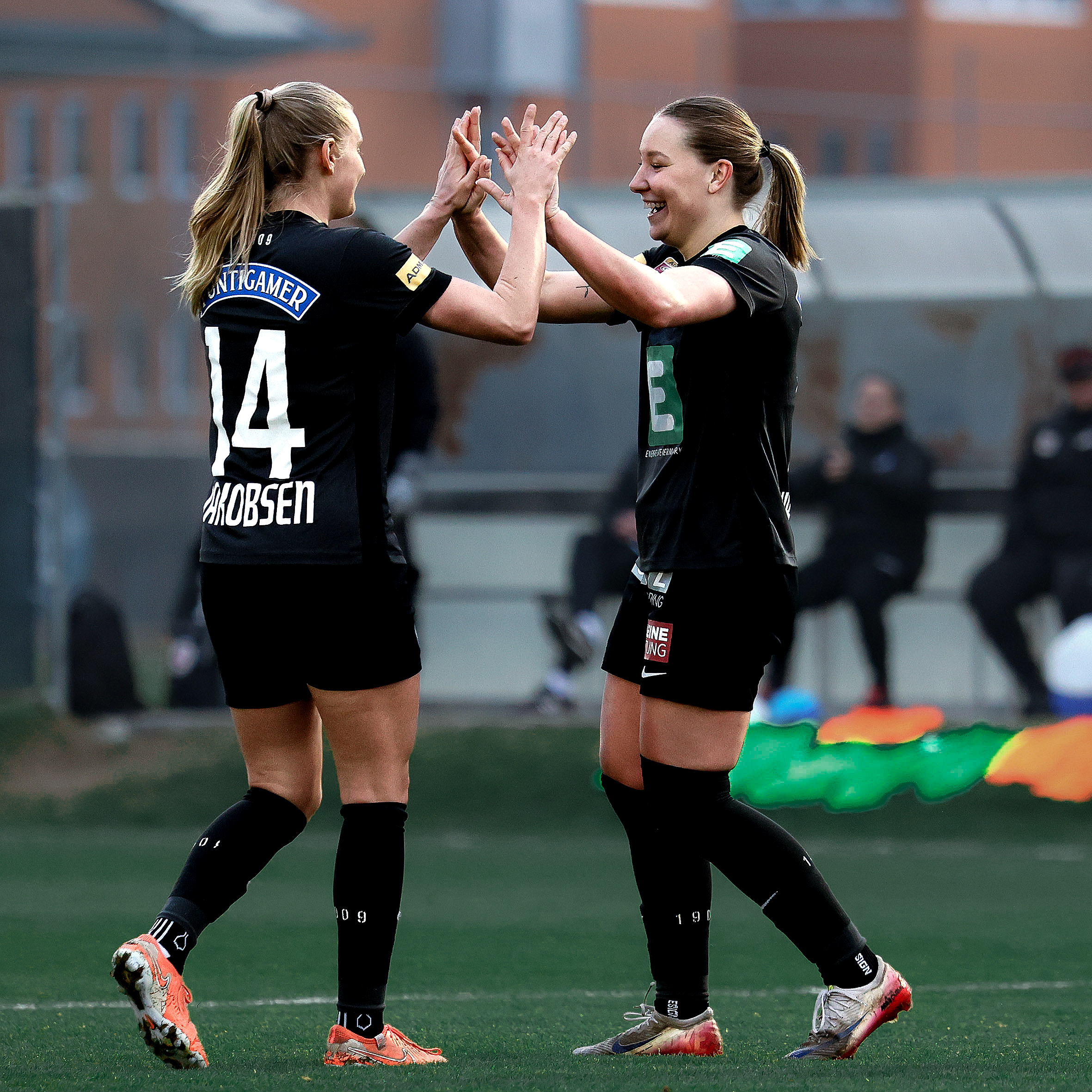 Zwei Frauen in schwarzen Trikots freuen sich gemeinsam und klatschen ein.