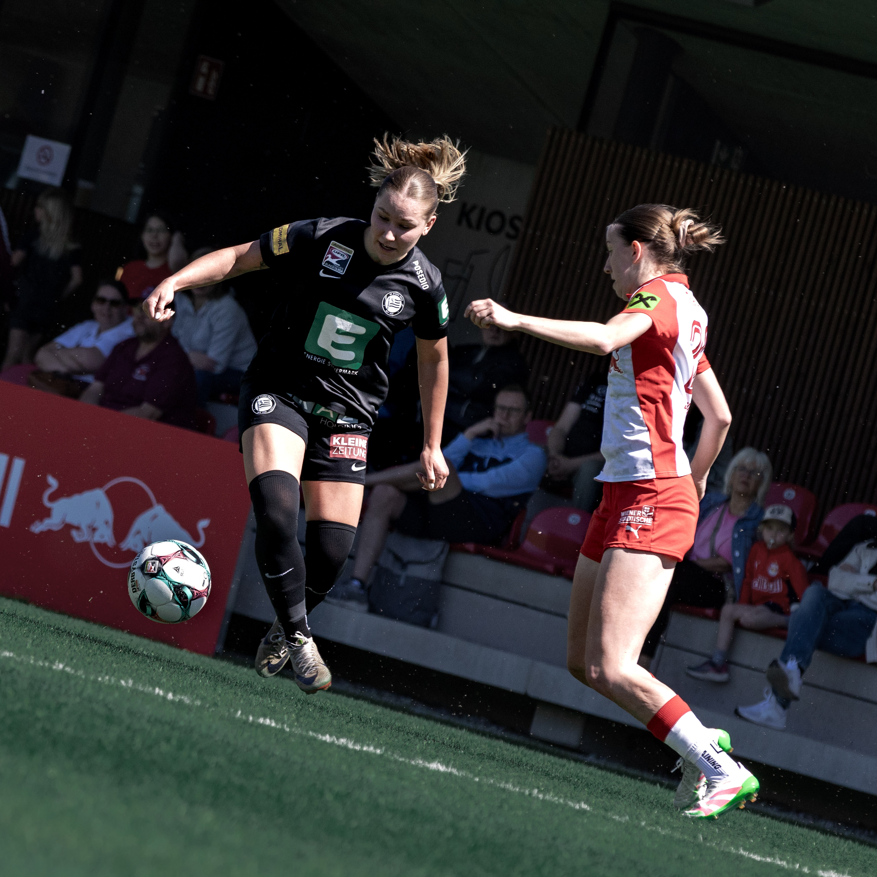 Eine Frau in schwarzem Trikot hat den Ball am Fuß eine Frau in rot-weißem Trikot steht davor.
