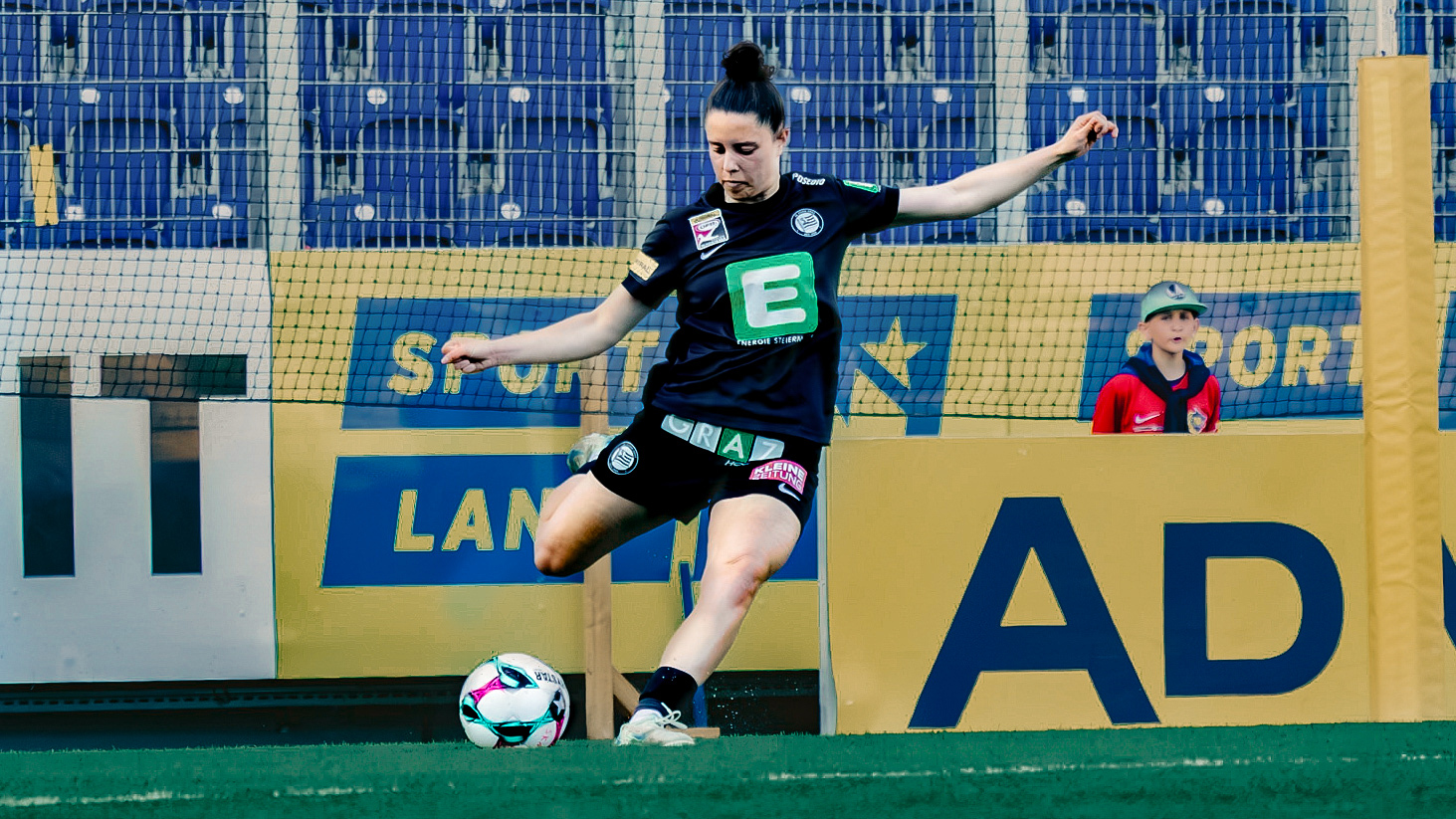 Eine Frau im schwarzem Trikot schießt den Ball.