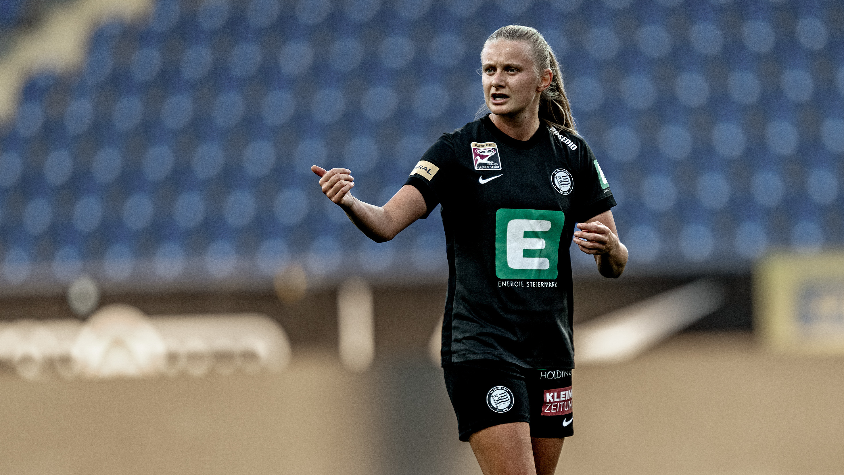 Eine Frau in schwarzem Trikot hebt beide Hände.