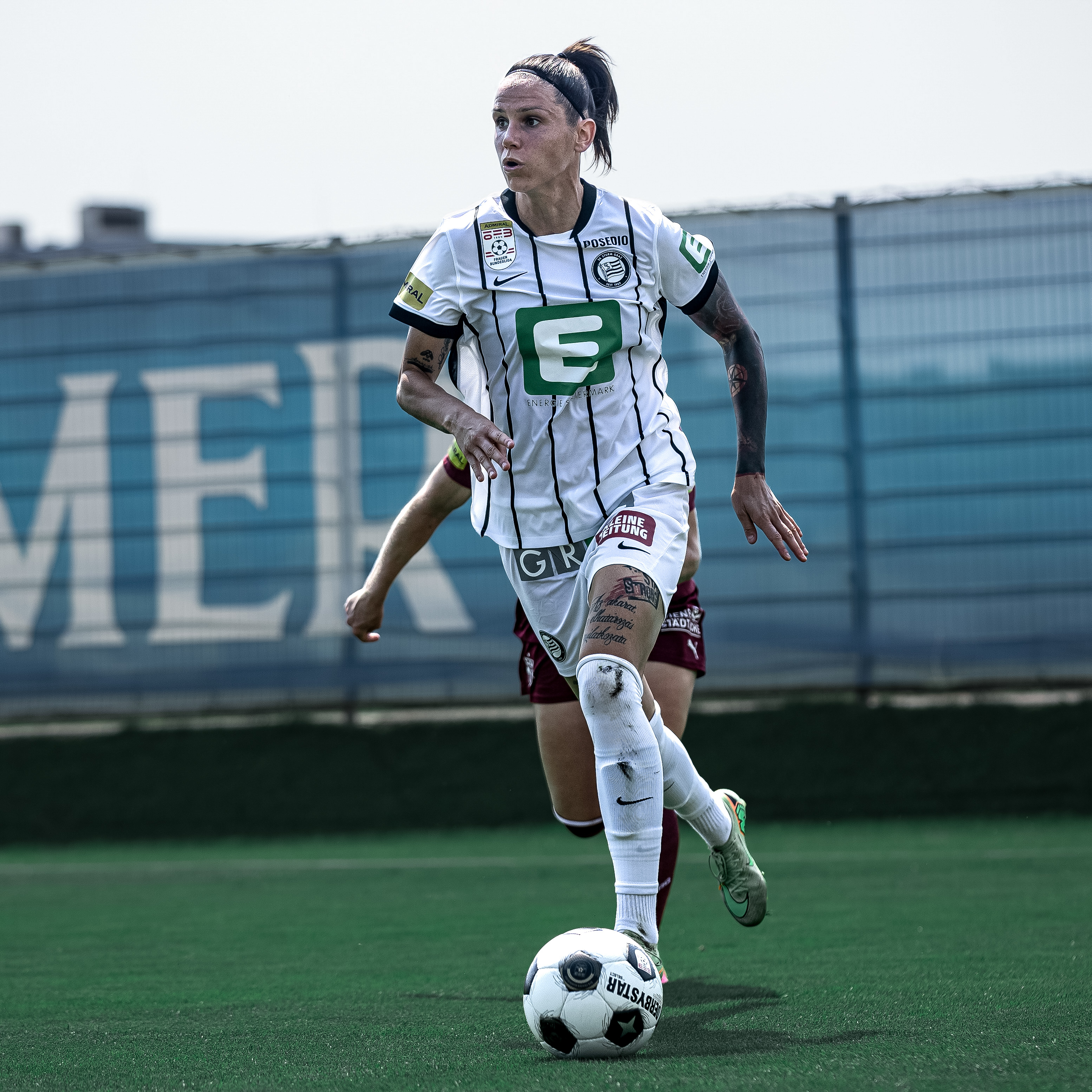 Eine Frau in weißem Trikot führt den Ball mit dem linken Fuß.