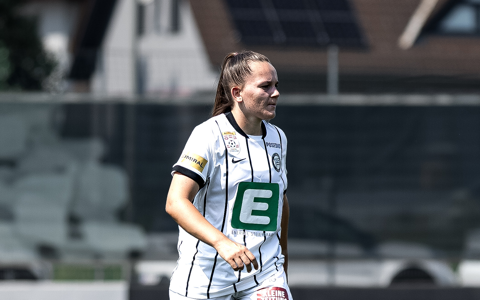 Eine Frau in weißem Trikot sieht man von der Seite und sie schaut konzentriert.