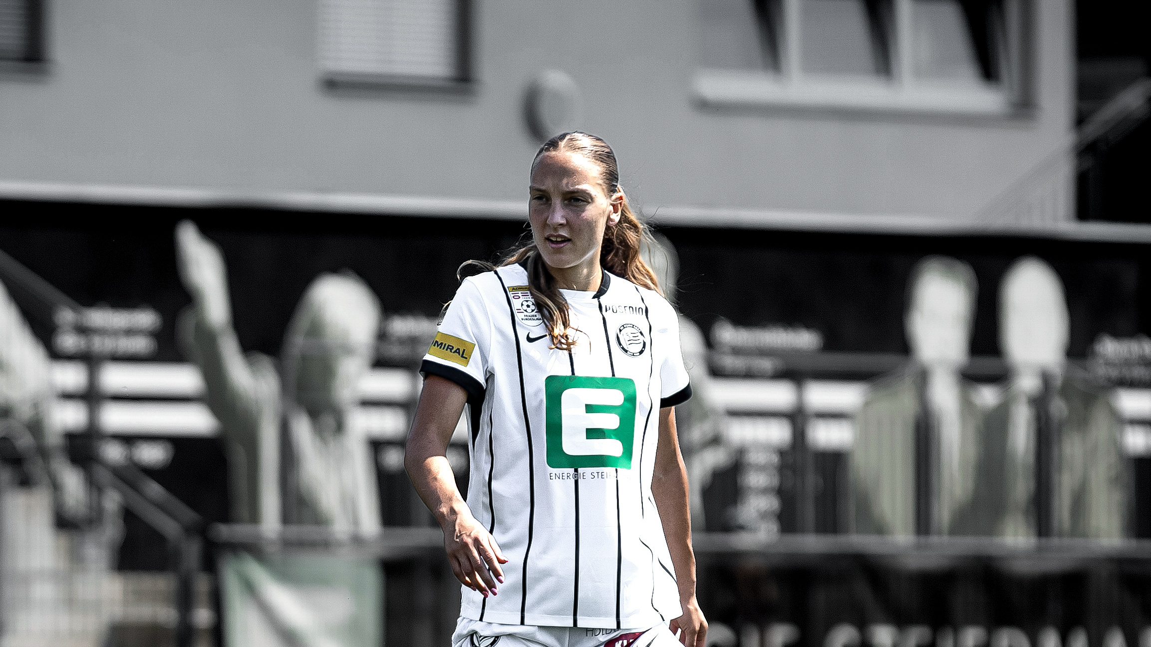 Eine Frau in weißem Trikot schaut konzentriert.