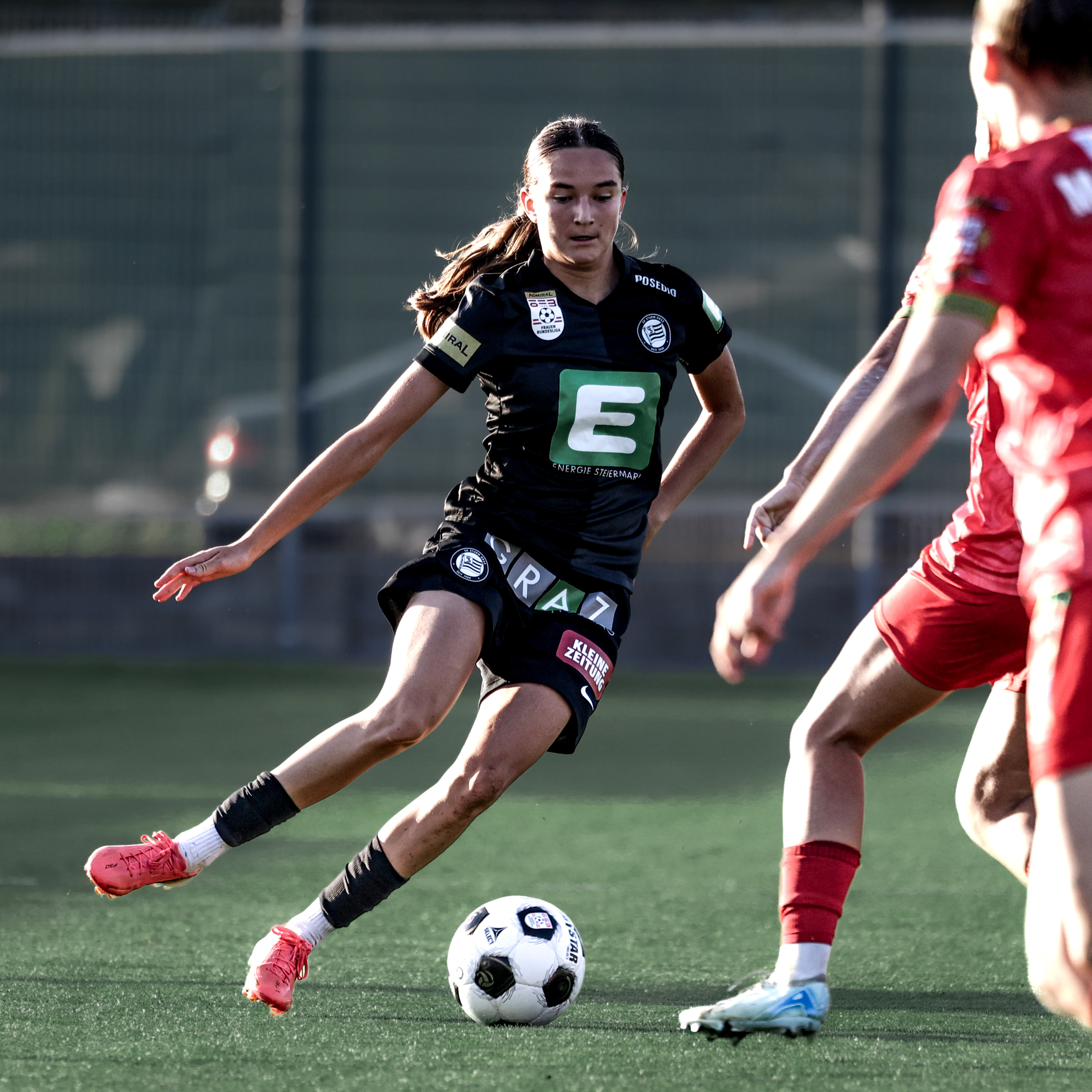 Eine Frau hat den Ball am Fuß und steht auf einem Bein.