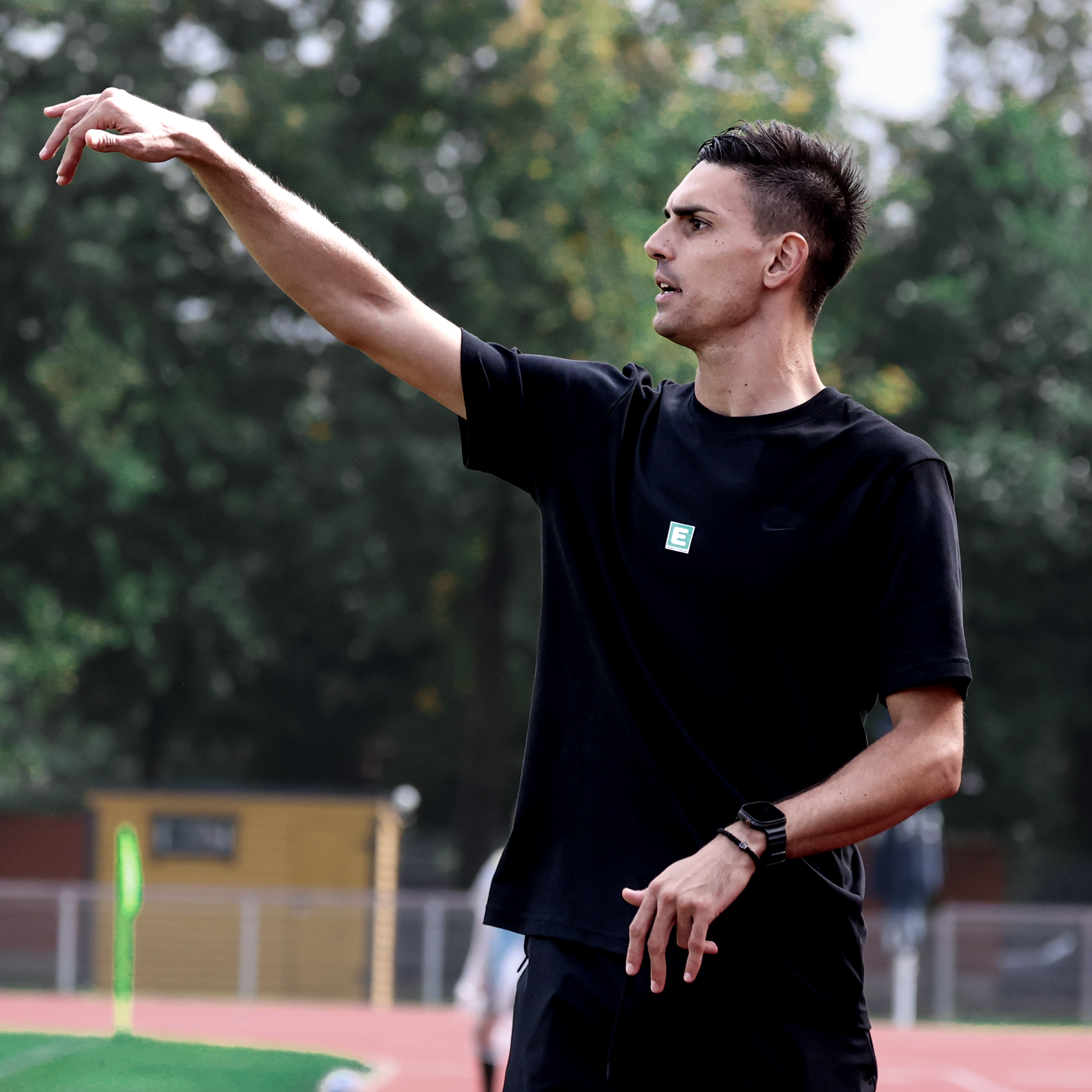 Ein Mann mit einem schwarzen Shirt hebt die rechte Hand in die Höhe.