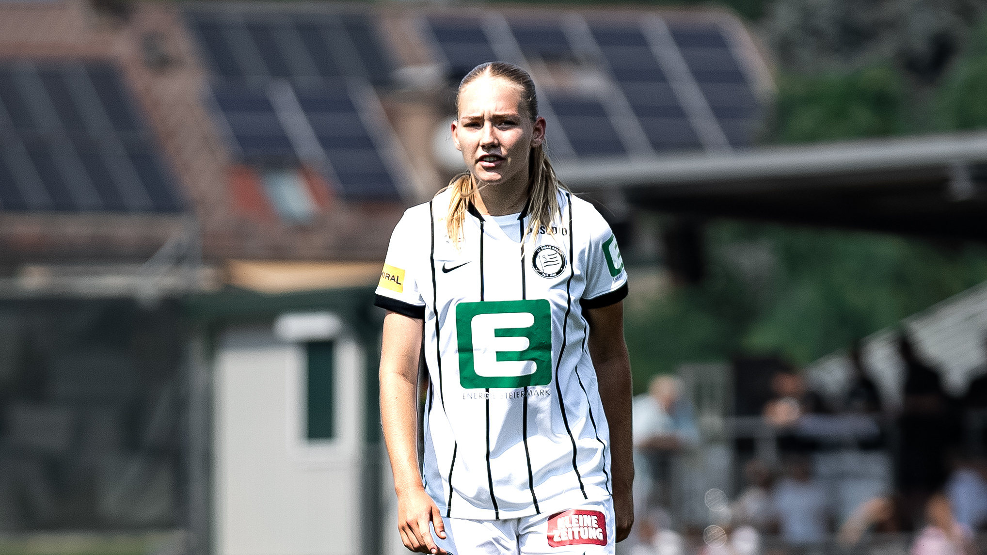 Man sieht eine Frau in weißem Trikot die konzentriert schaut.