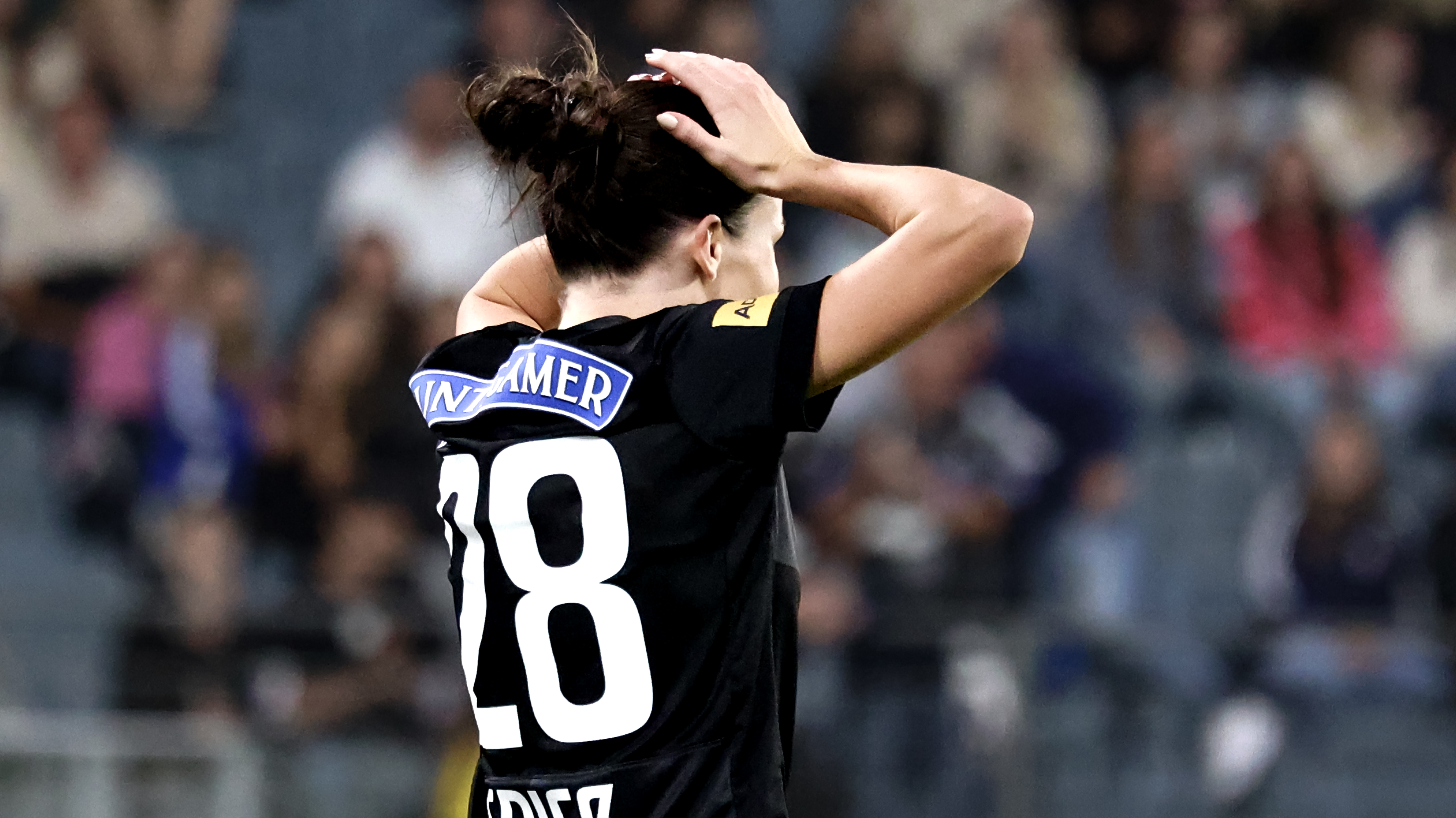 Eine Frau in schwarzem Trikot hält die Hände auf den Kopf.