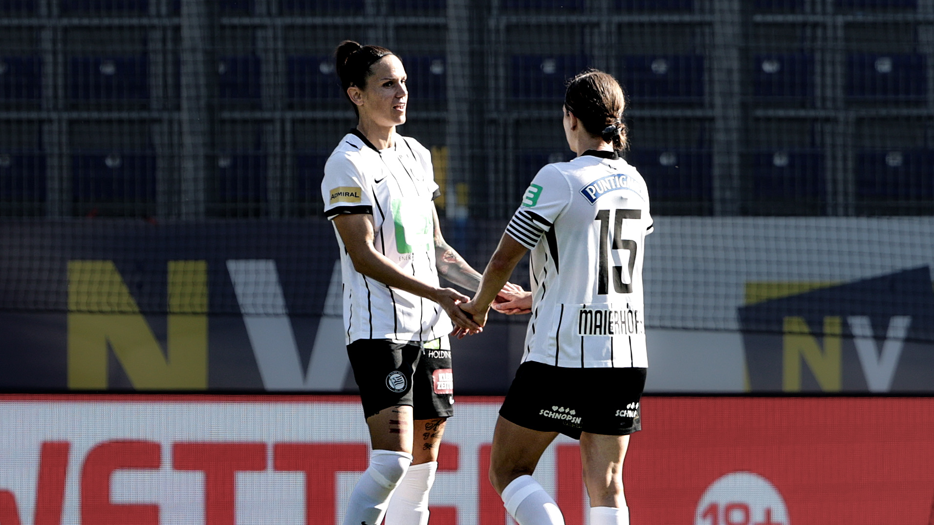 Zwei Frauen in einem weißen Trikot klatschen ein.