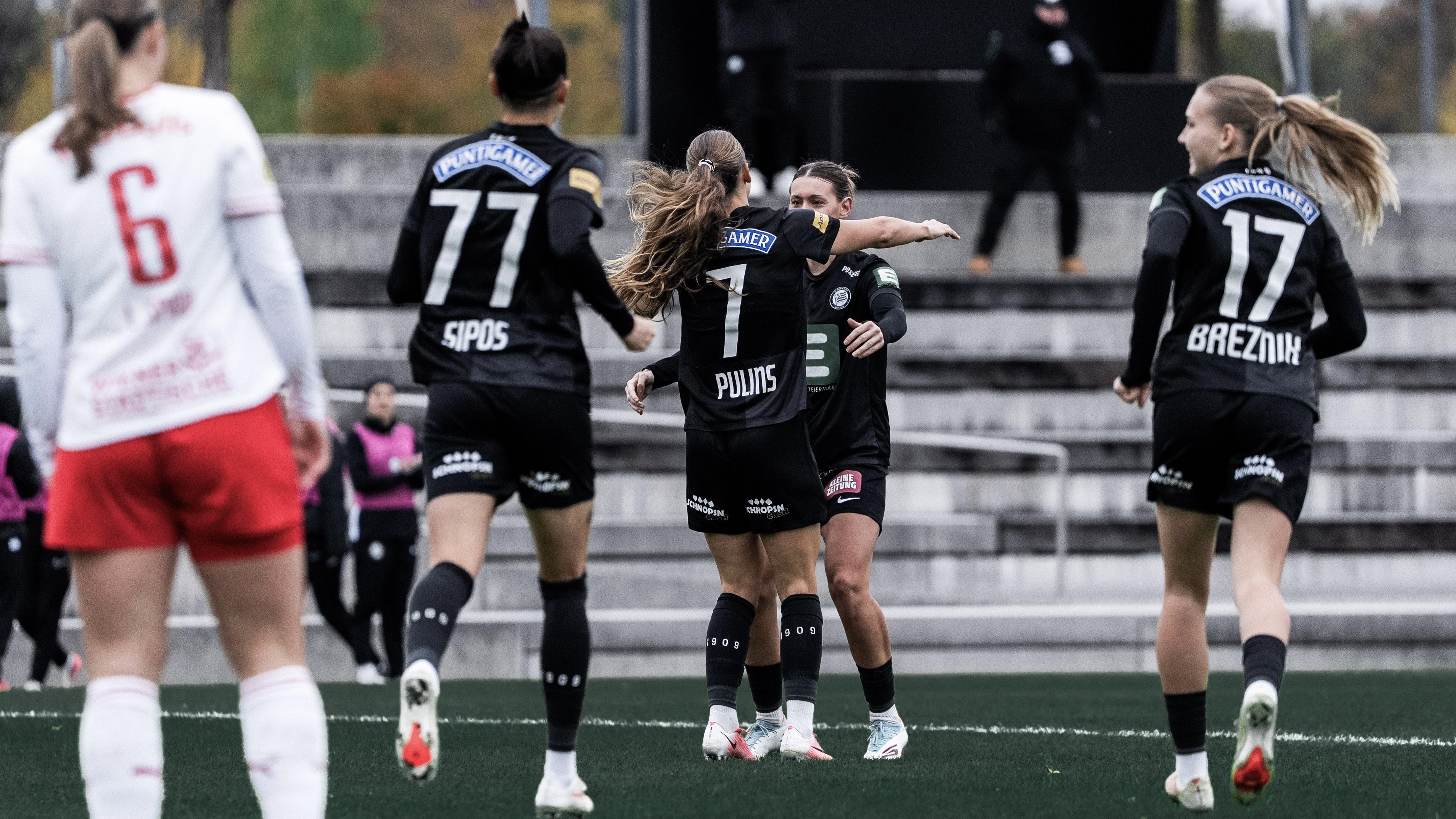 Zwei Frauen in schwarzem Trikot umarmen sich.