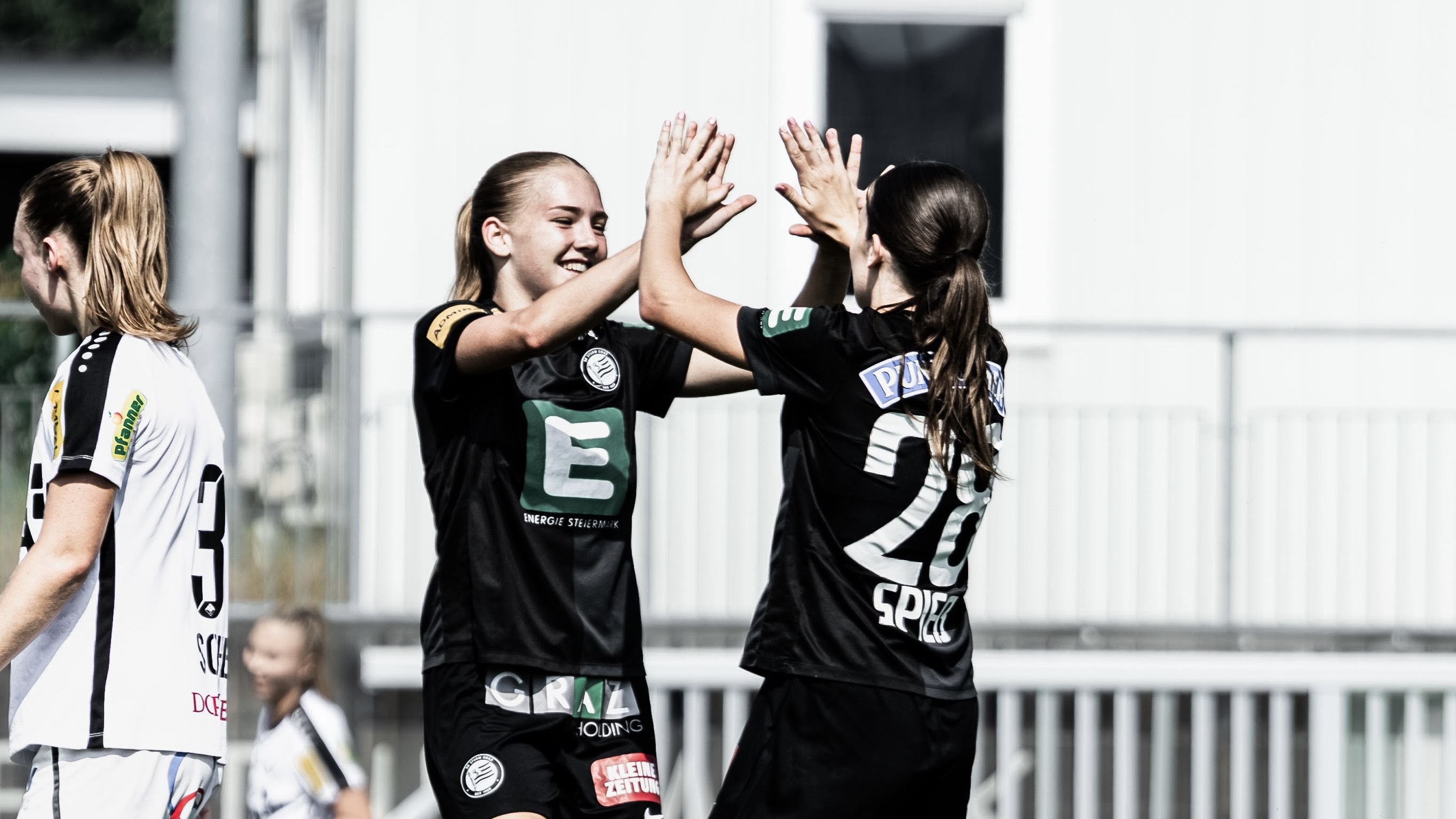 Zwei Frauen in schwarzem Trikot klatschen ein.