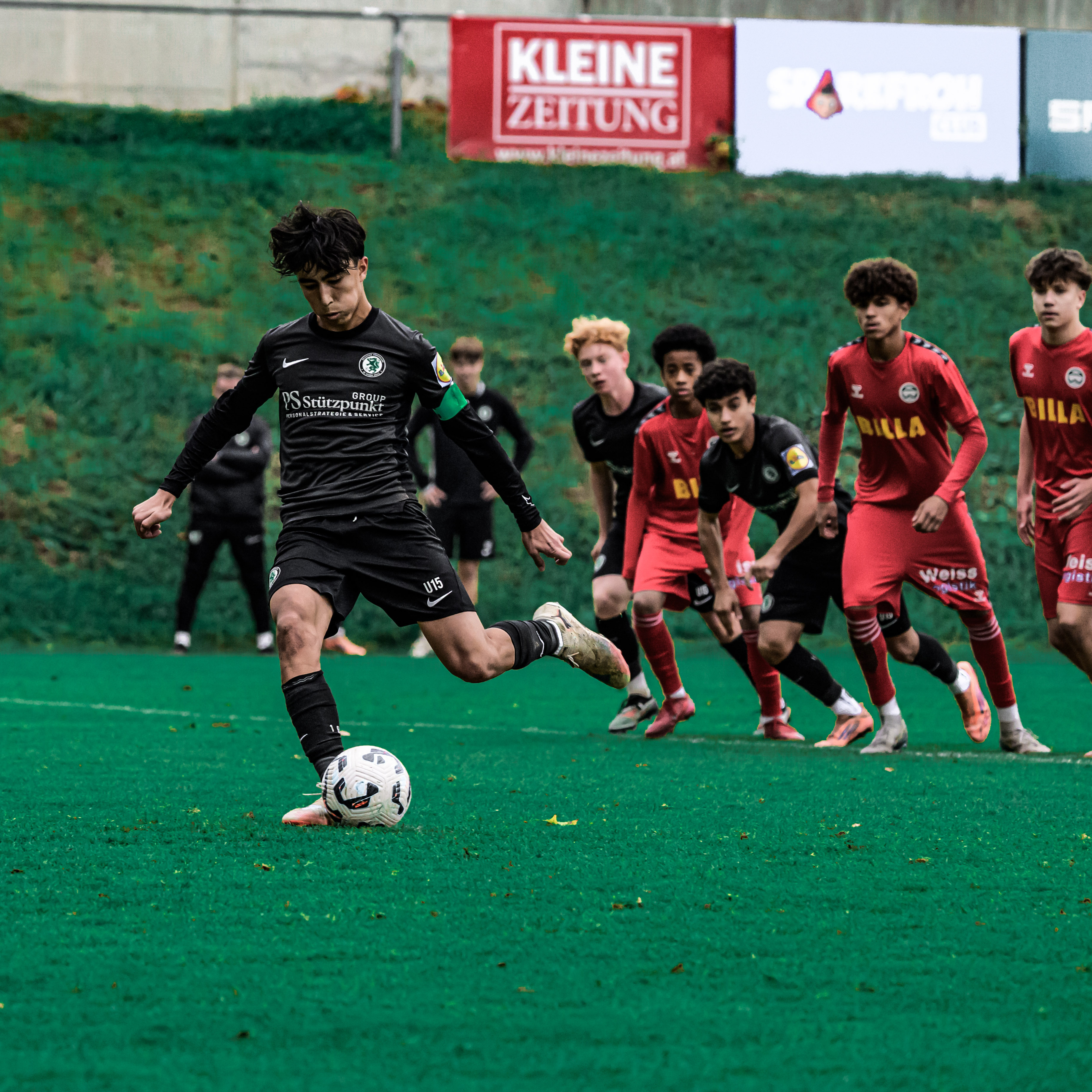 Ein junger Spieler schießt, viele schauen zu.