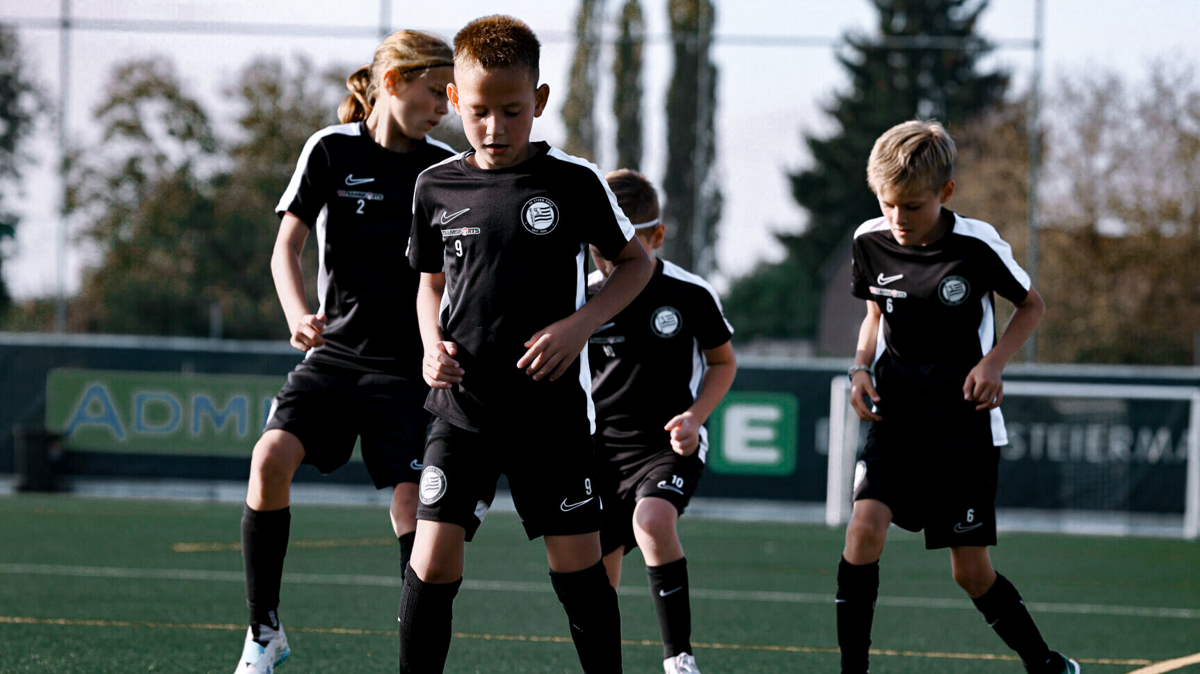 Junge Mädchen und Burschen spielen Fußball