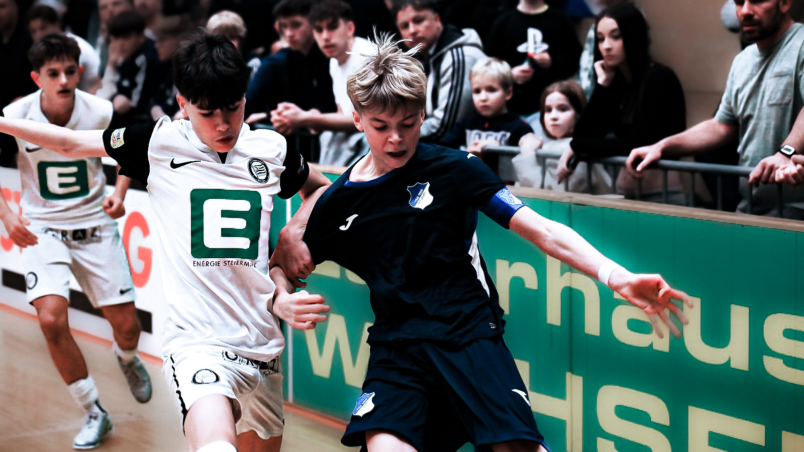 Ein Jugendlicher in weiß und einer in dunkelblau kämpfen um den Ball