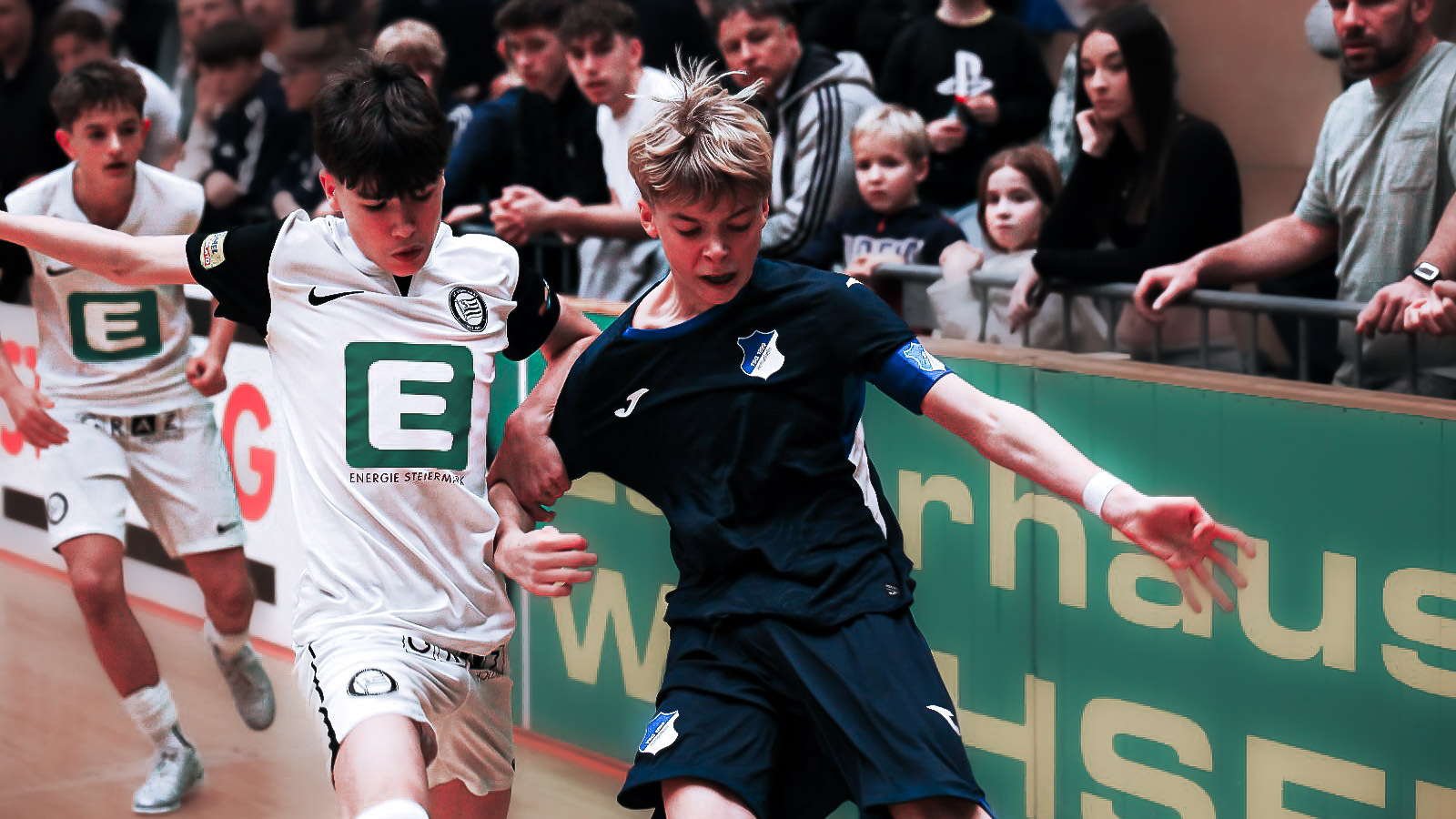 Ein Jugendlicher in weiß und einer in dunkelblau kämpfen um den Ball