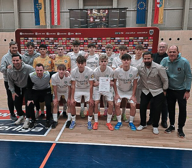 Eine Fußballmannschaft macht ein Gruppenbild in einer Halle.