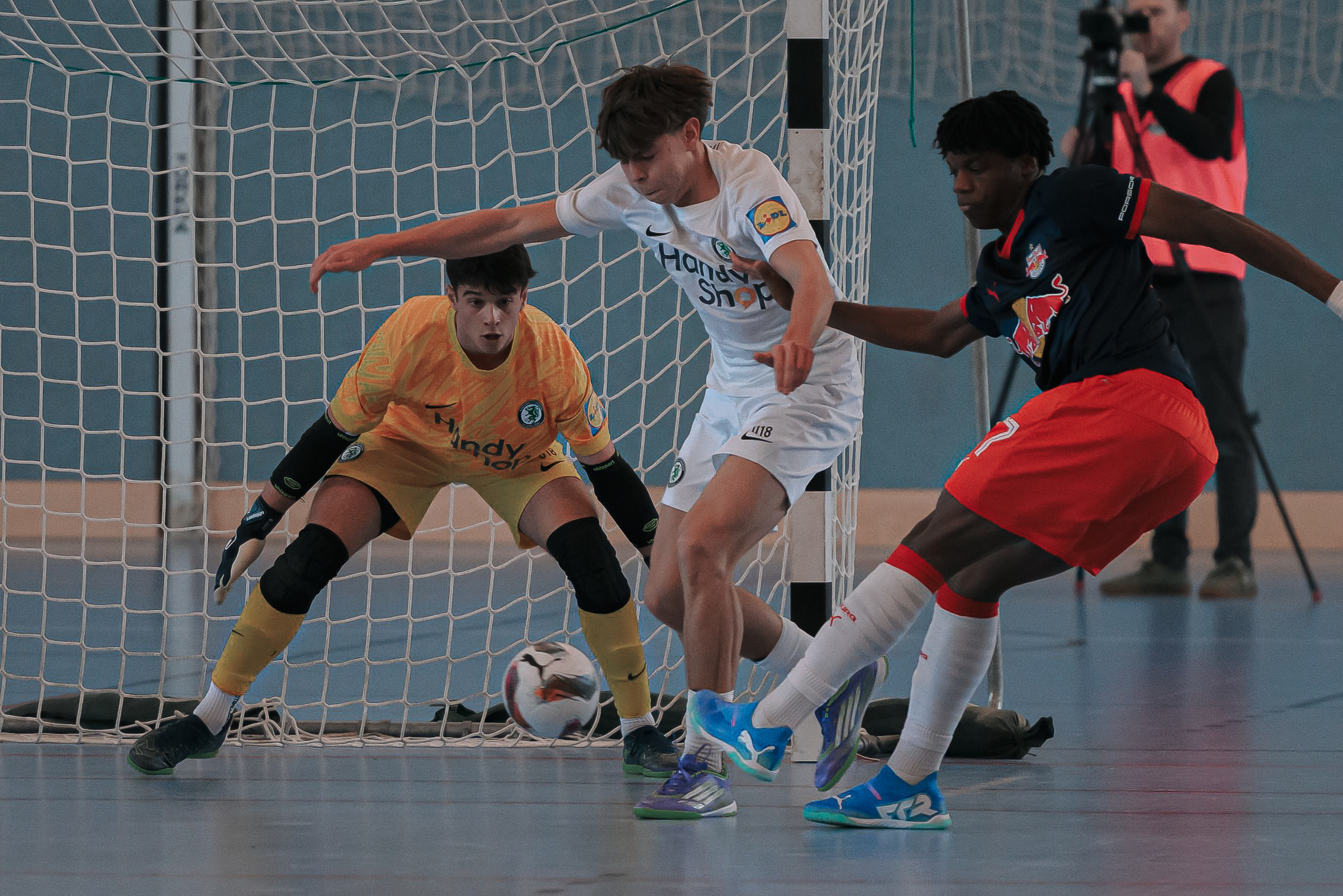 Drei Burschen spielen Fußball in der Halle