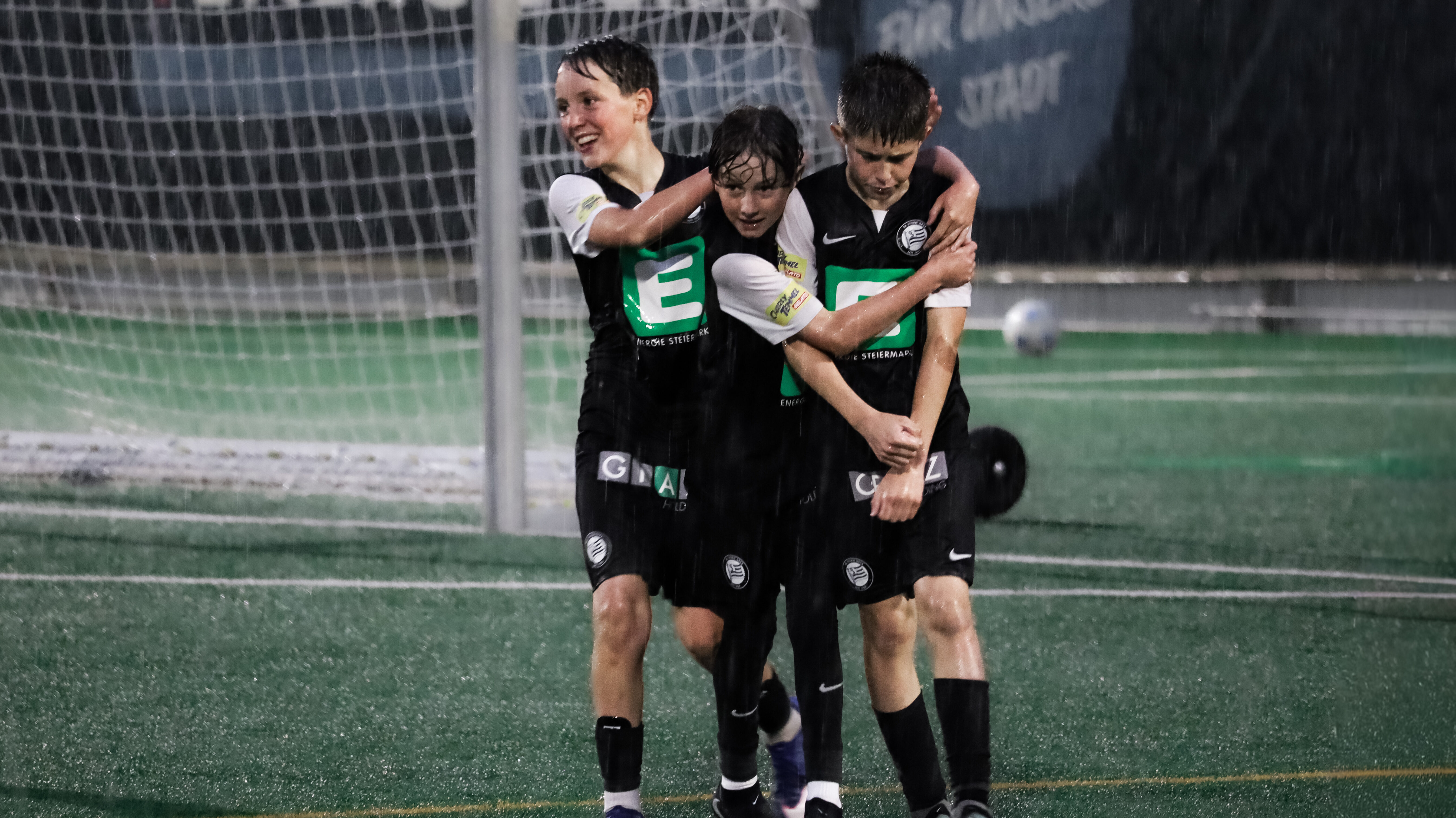 Drei junge Spieler in schwarz jubeln