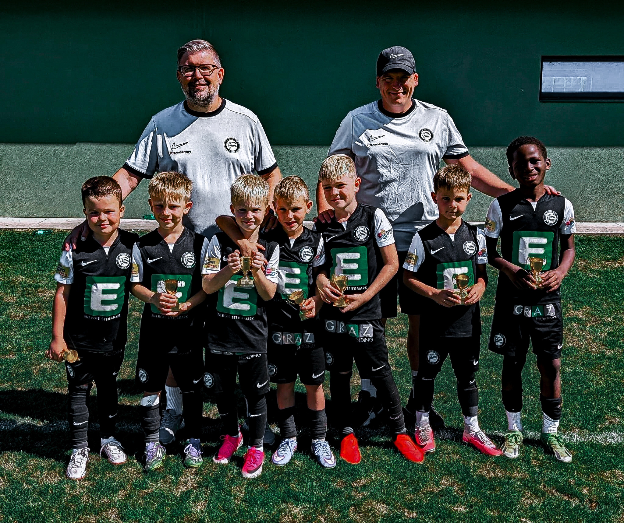 Eine junge Fußballmannschaft mut zwei Betreuern.