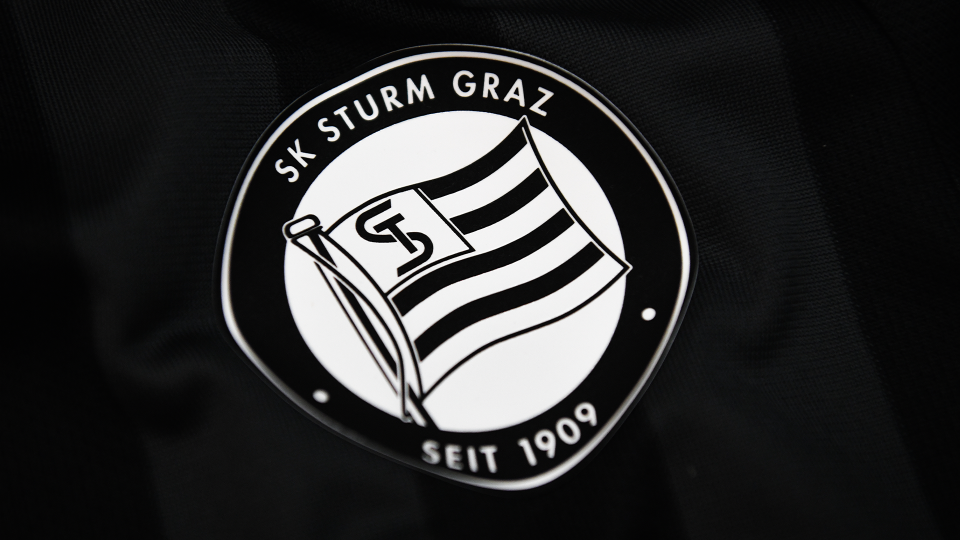 Logo auf schwarz-grau gestreiftem Hintergrund