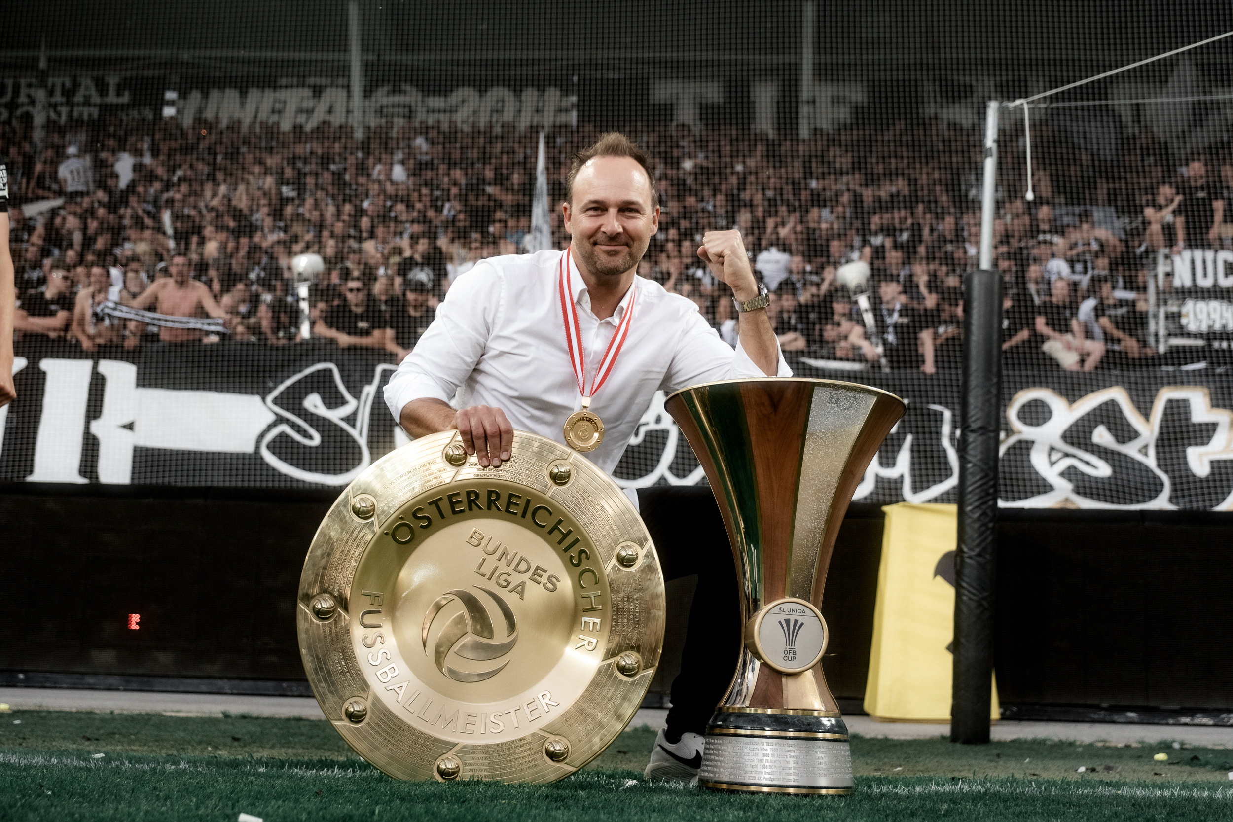 Ein jubelt sitzend vor zwei Trophäen