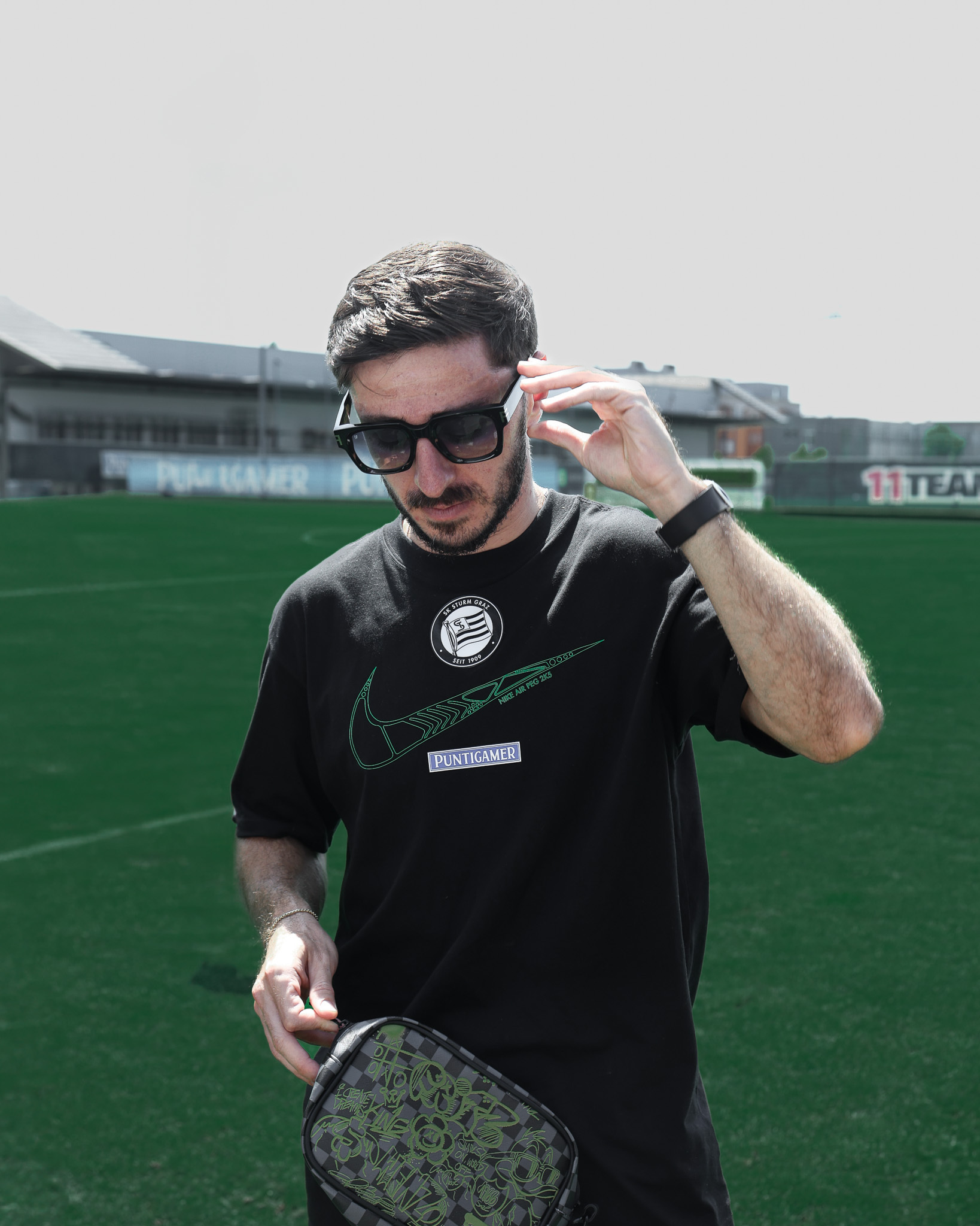 Mann mit Sonnenbrille am Fußballplatz.