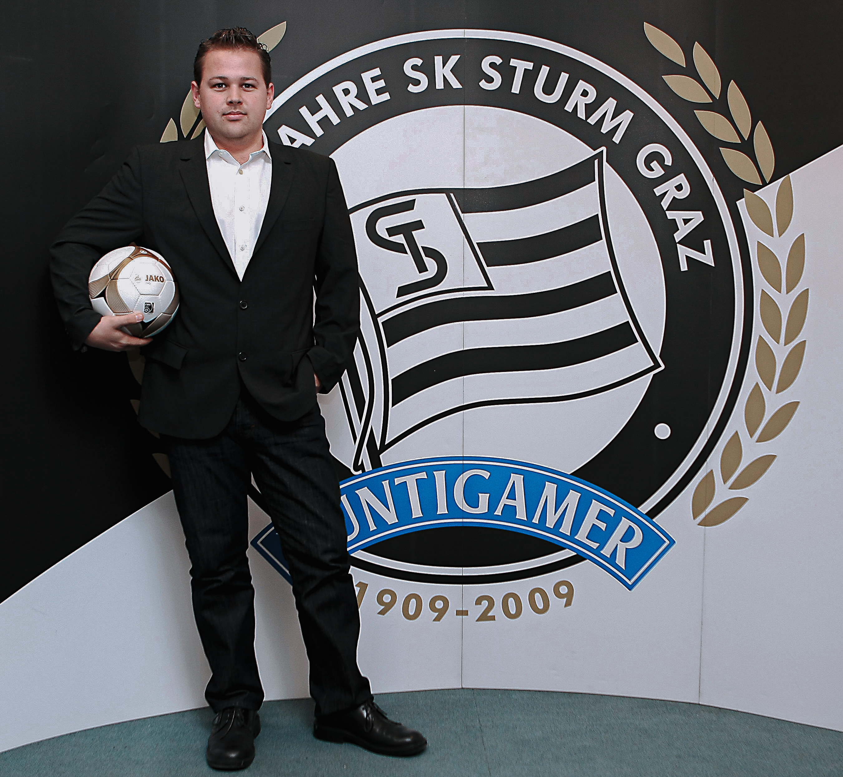Ein Mann mit einem Ball vor einem Logo