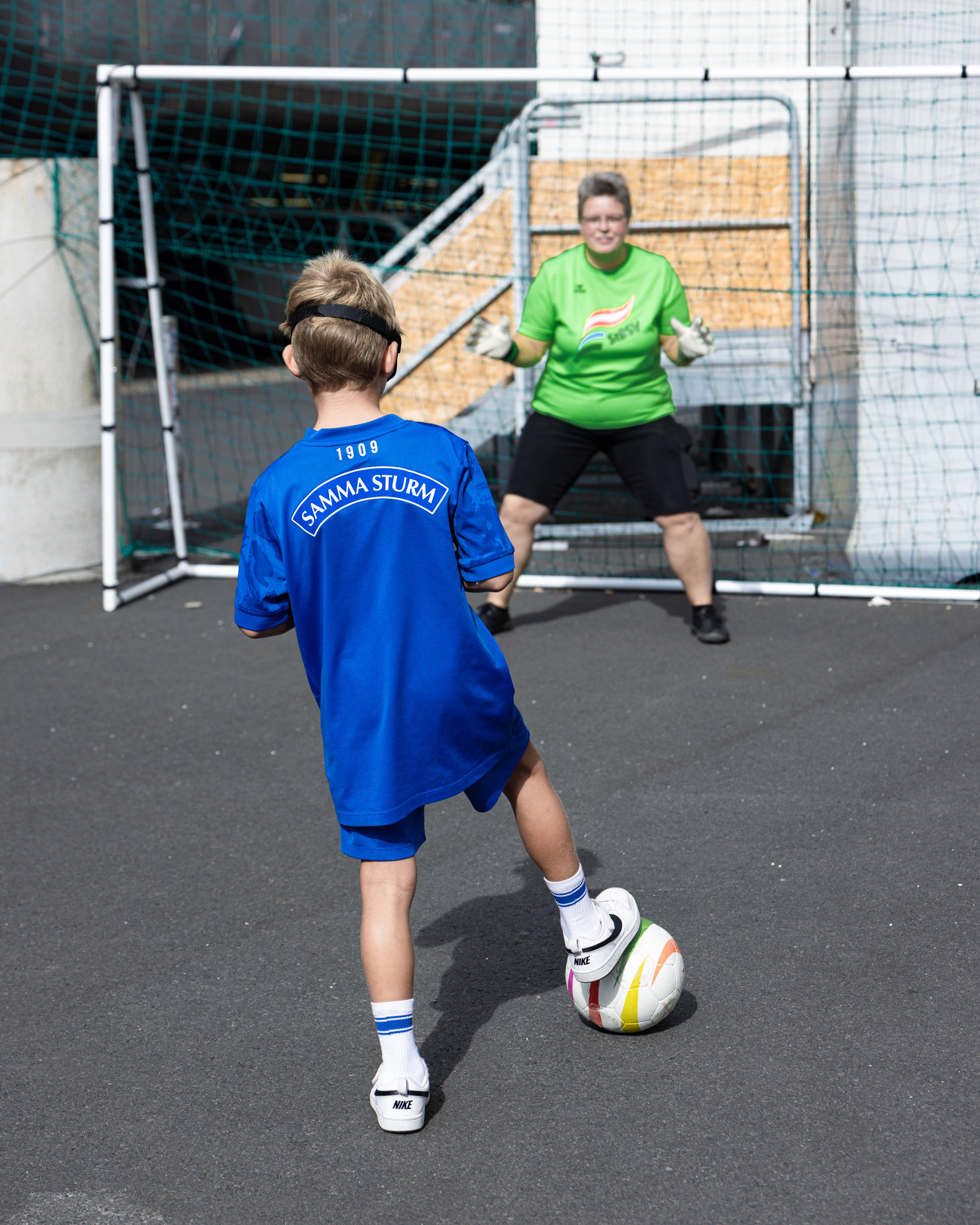 Kind mit Augenbinde versucht den Rasselball ins Tor zu befördern.